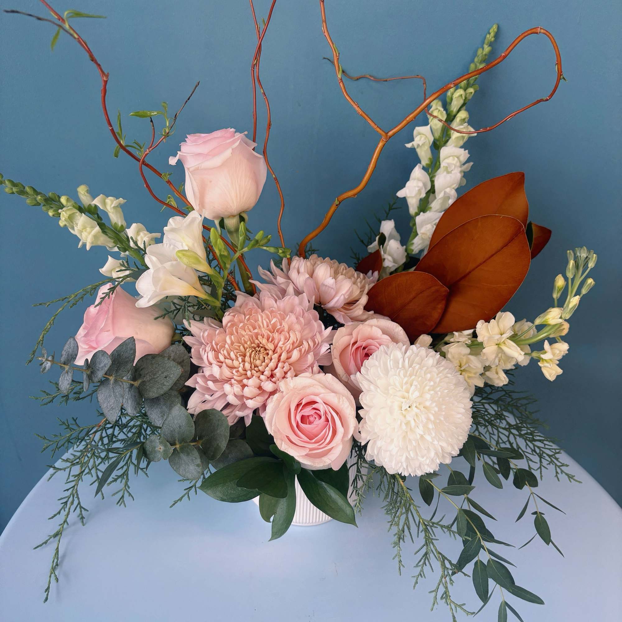 Pink and white floral arrangement in a white vase with tall branches