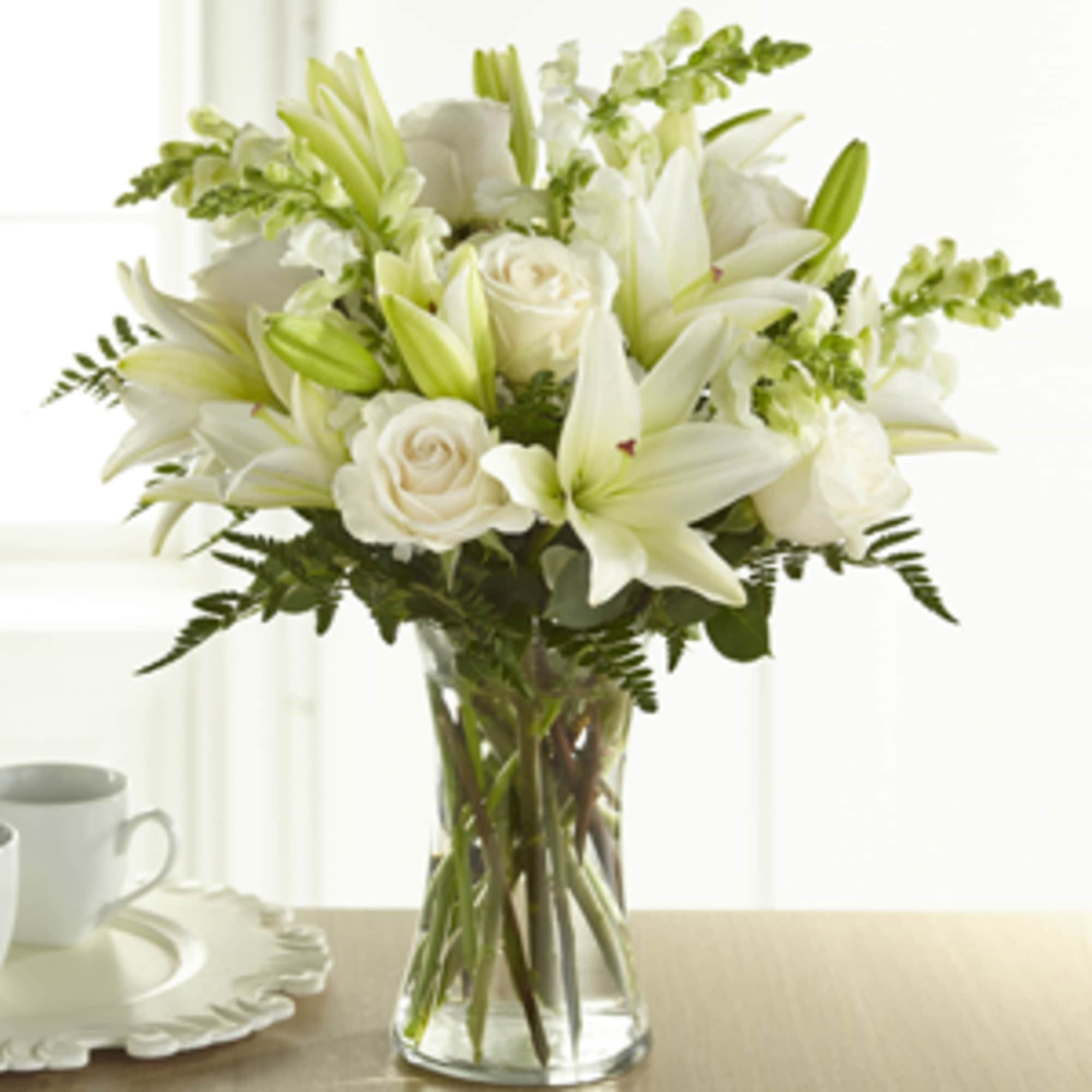 White lilies and roses arranged in a clear glass vase
