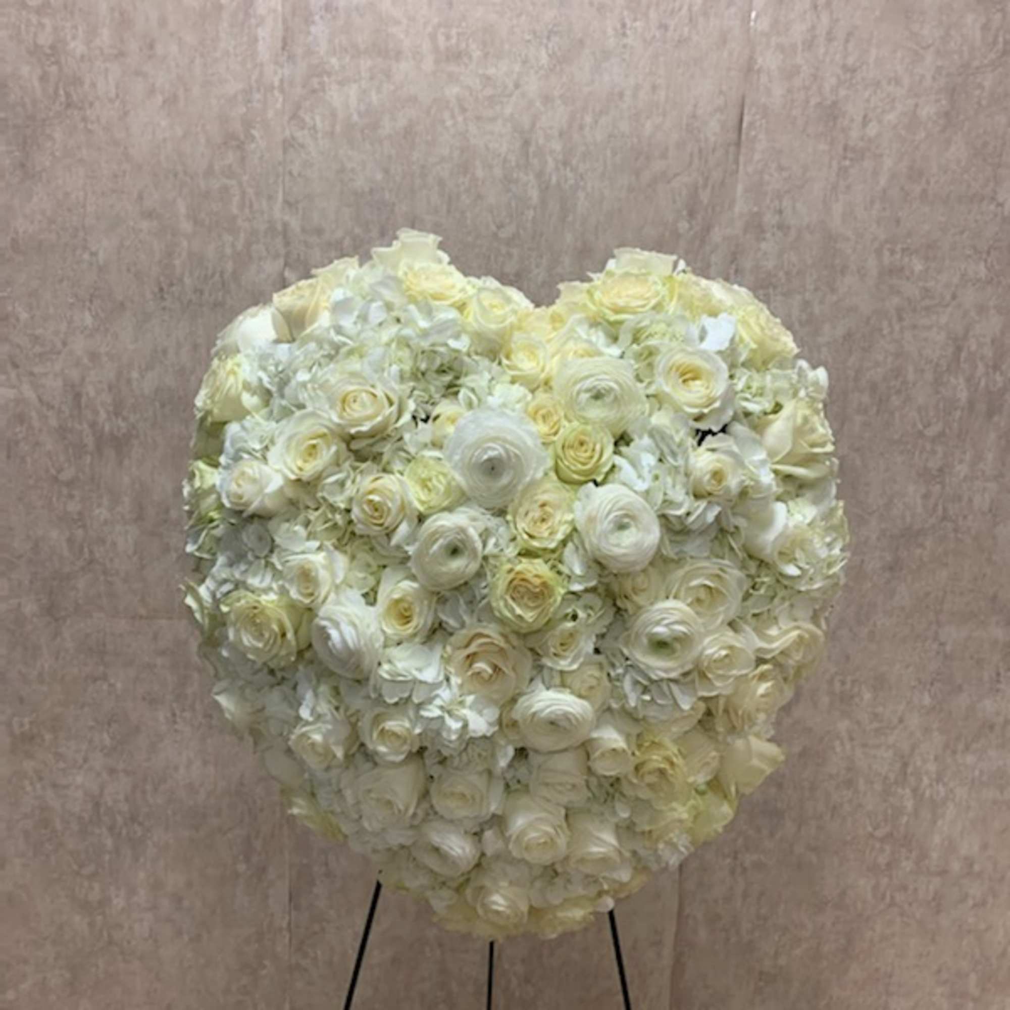 Heart-shaped standing arrangement of white and cream roses and hydrangeas on a metal easel
