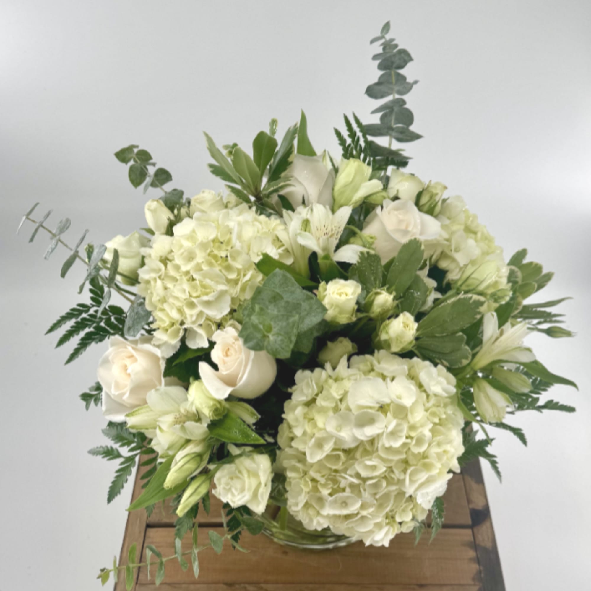 New beginnings deserve flowers! This all white arrangement includes roses, lisianthus, white