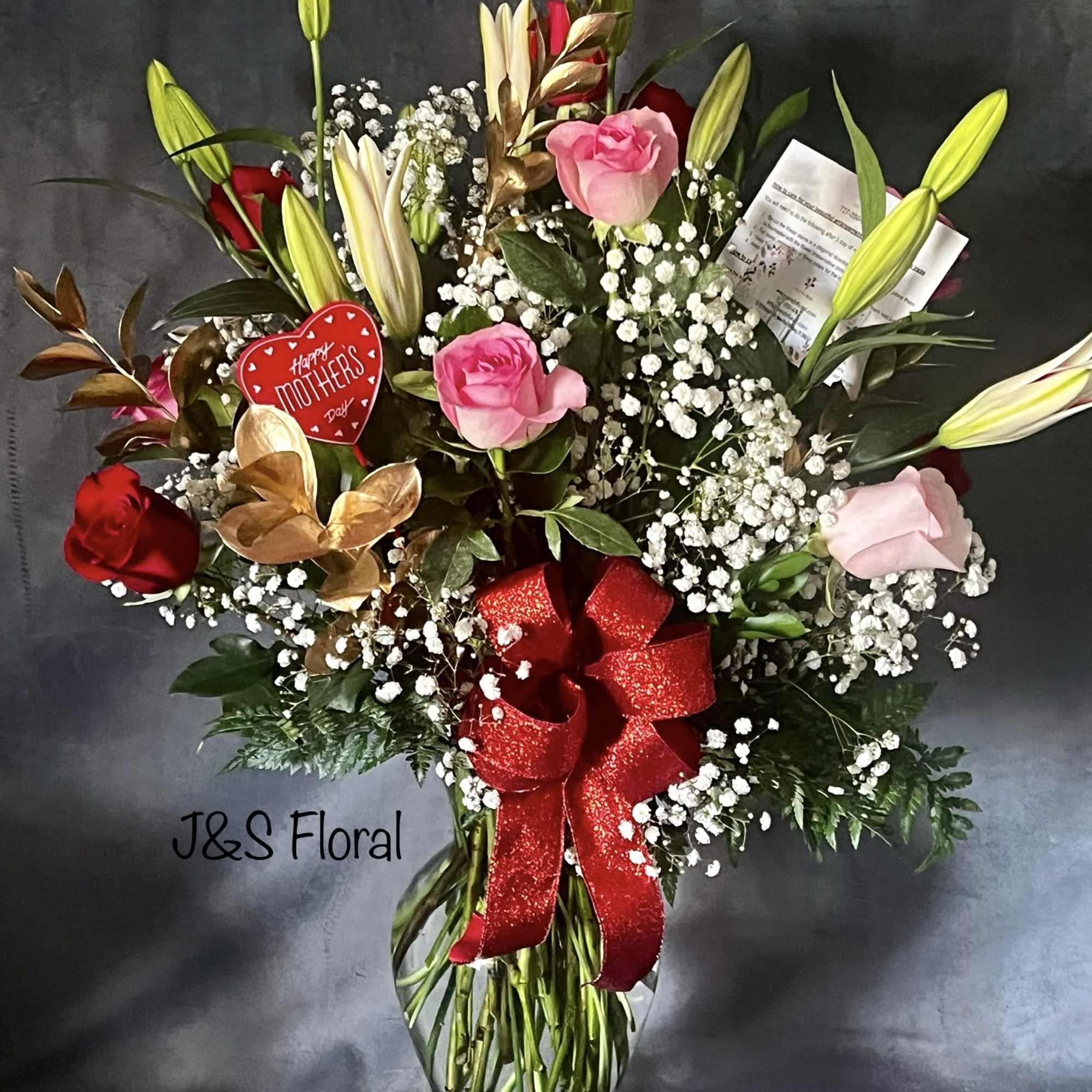 Bouquet of pink and red roses with white lilies in a glass vase
