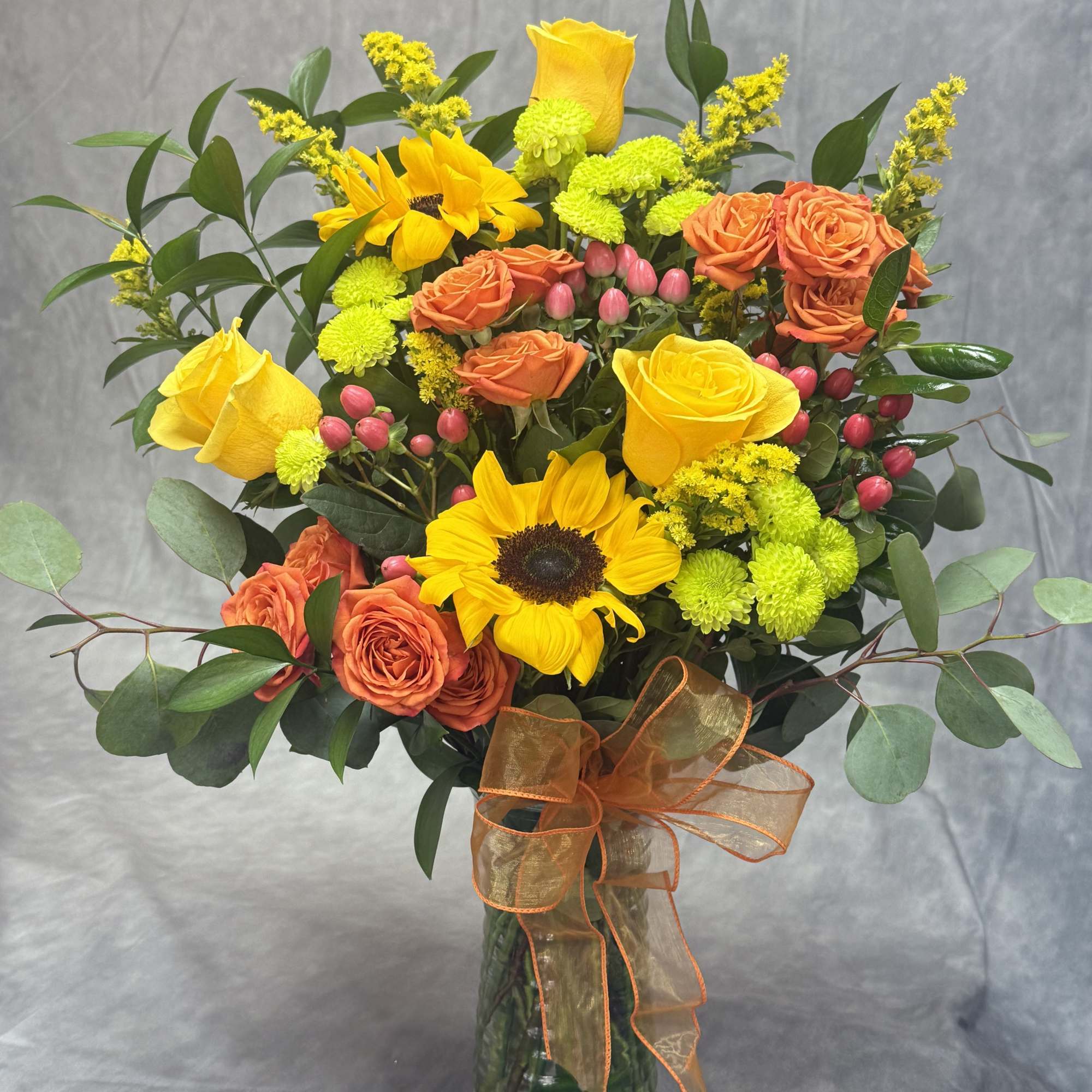 Bouquet of yellow sunflowers and orange roses in a glass vase