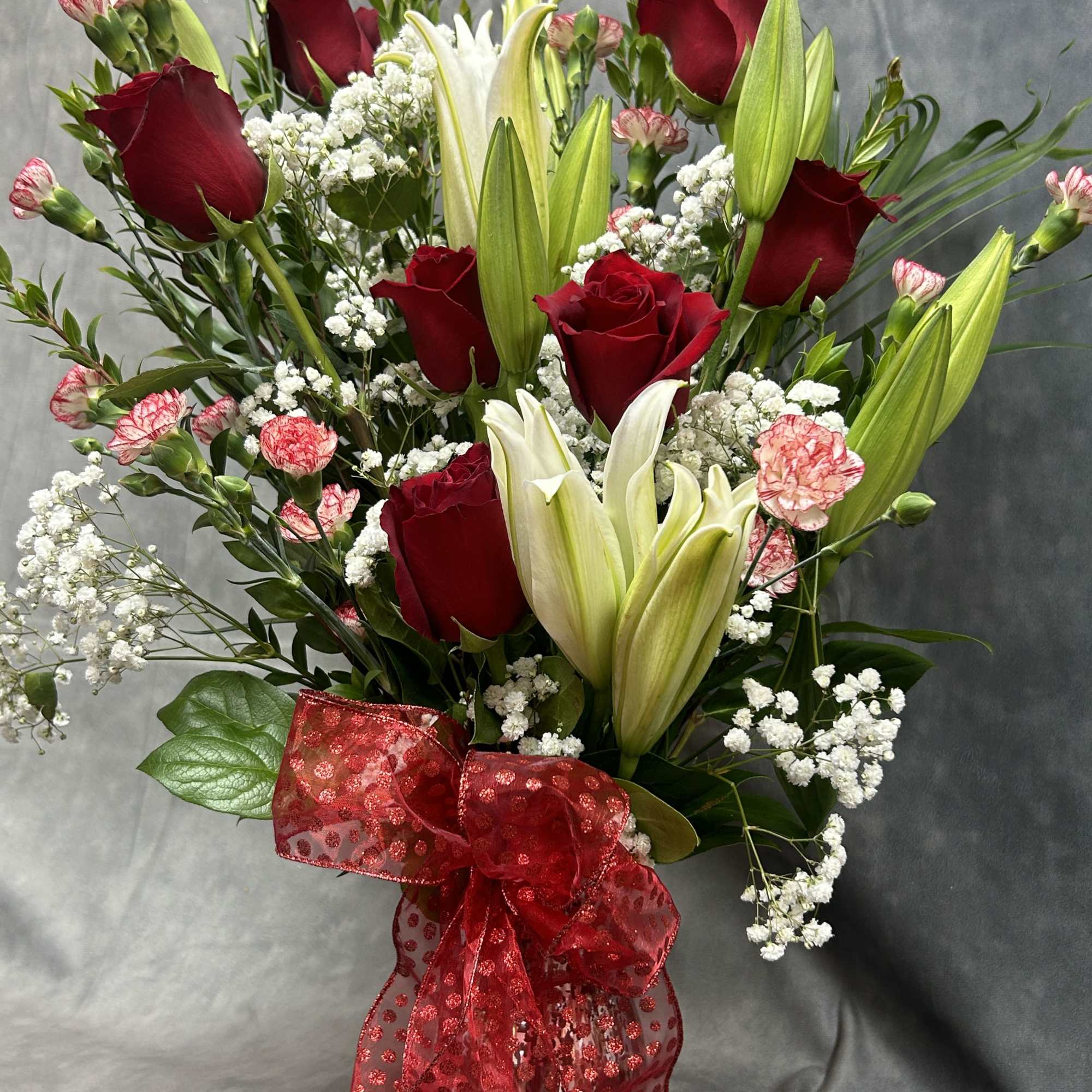 Bouquet of red roses and white lilies with baby's breath in a vase