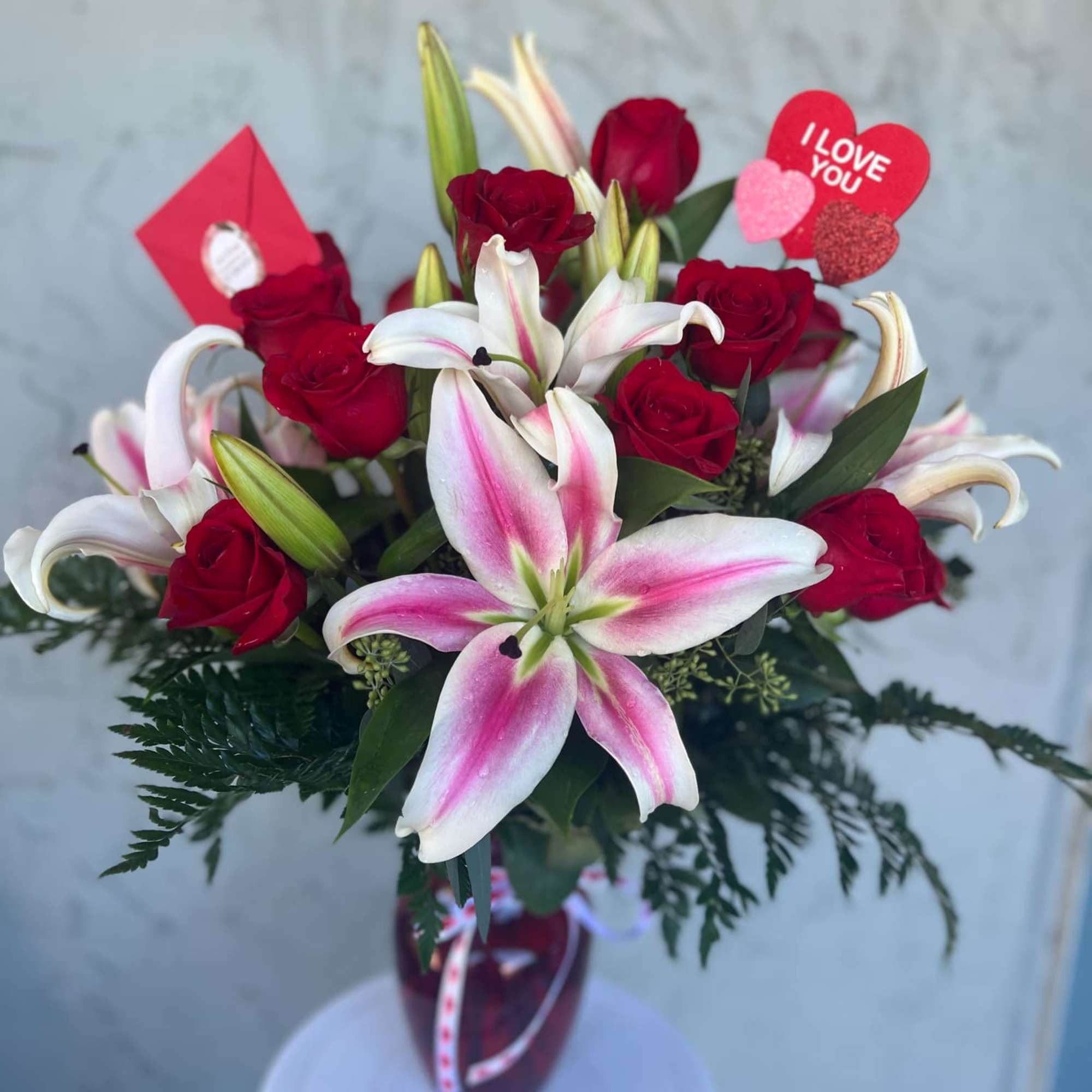 Bouquet of red roses and pink-white lilies in a vase with Valentine hearts