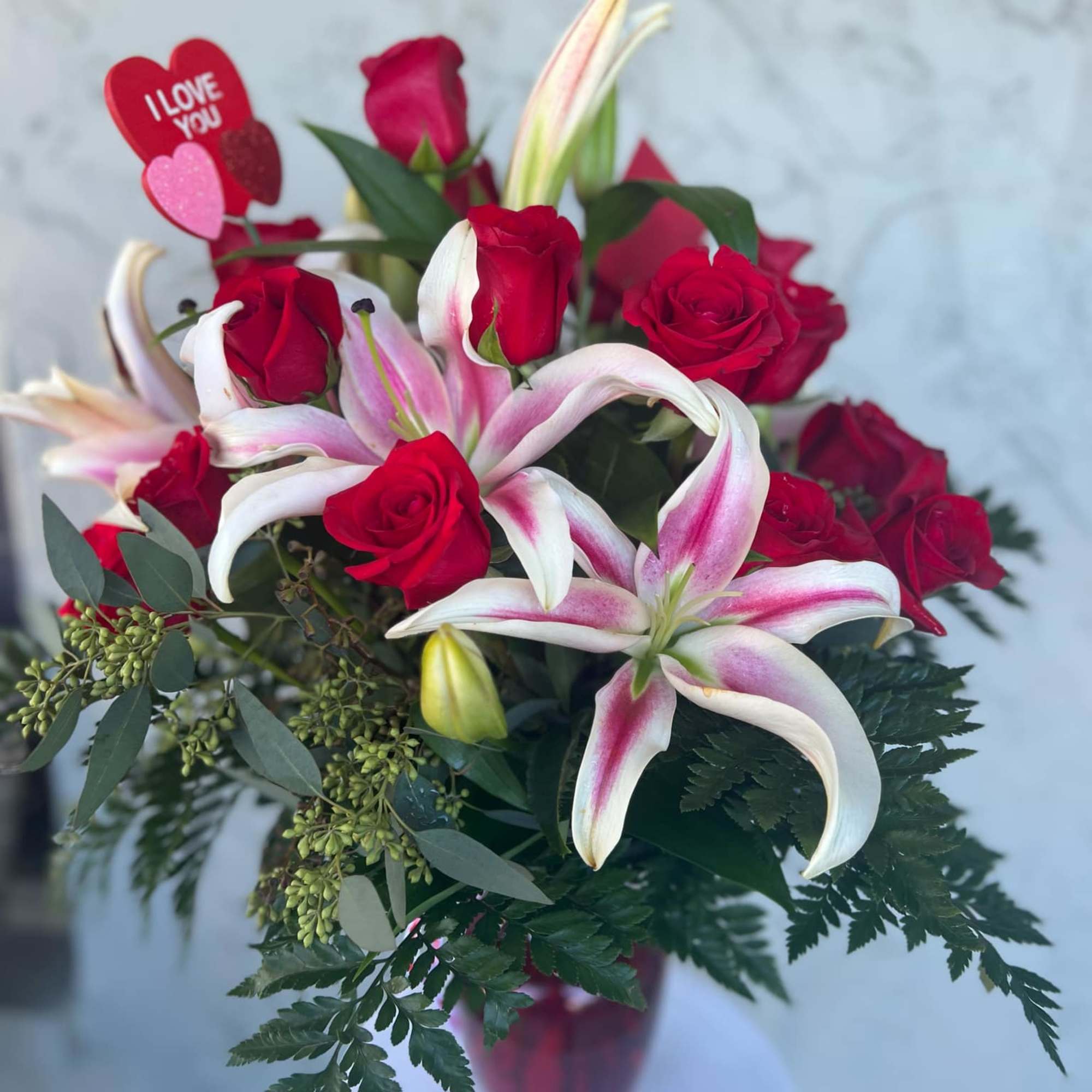 Bouquet of red roses and pink lilies with an "I love you" pick