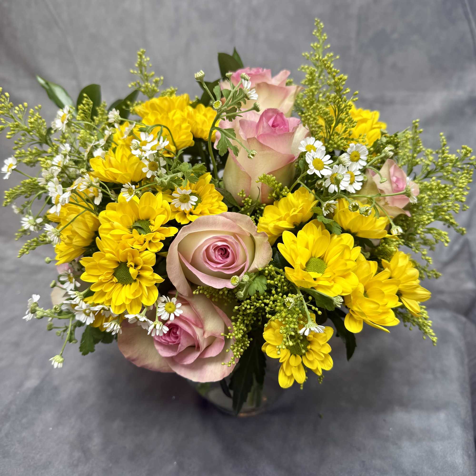 Pink roses and yellow daisies in a glass vase