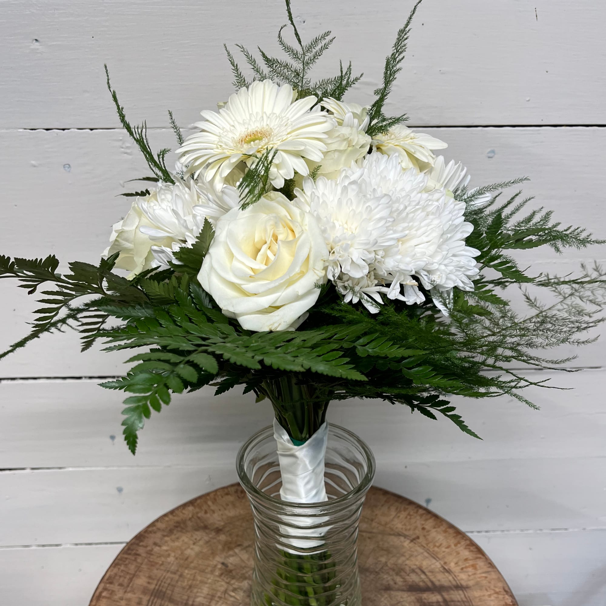 White rose and daisy bouquet in a clear glass vase