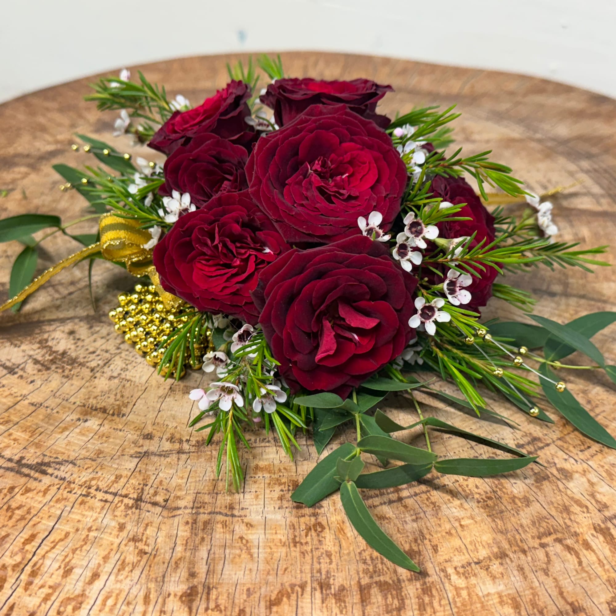 Compact bouquet of deep red roses with small white filler flowers