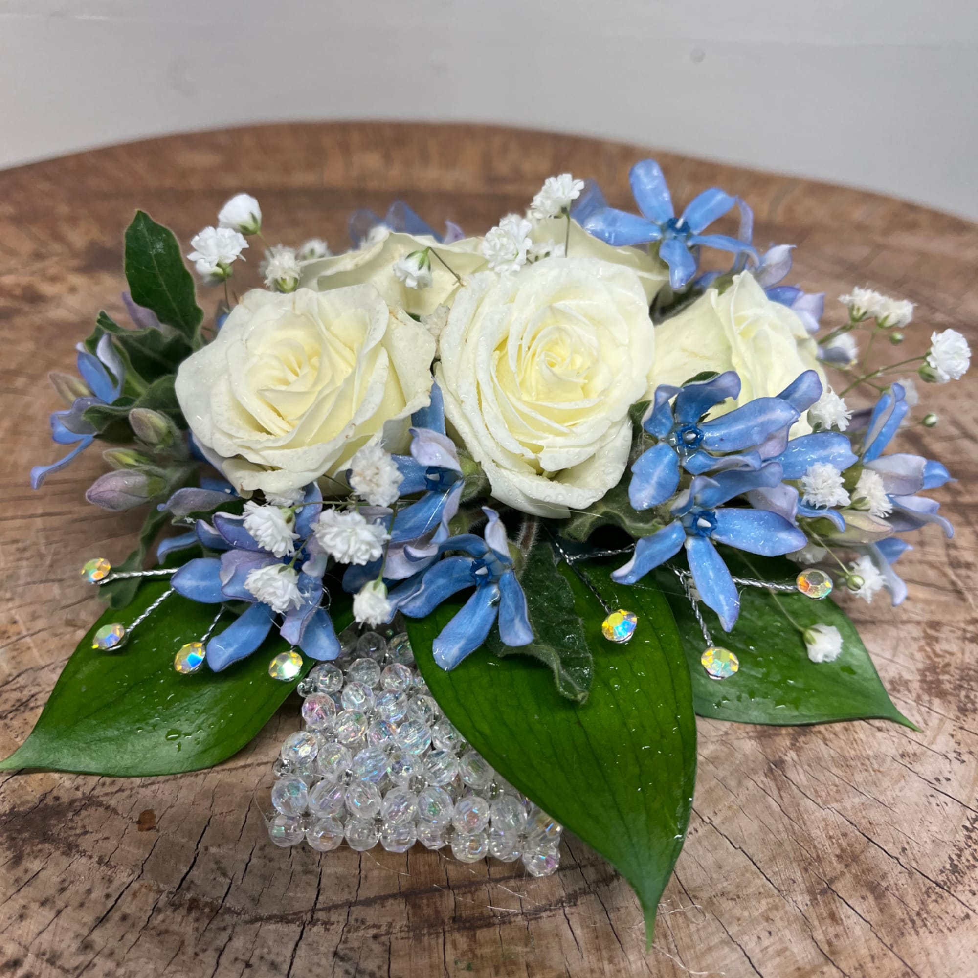 White roses with blue flowers in a beaded vase