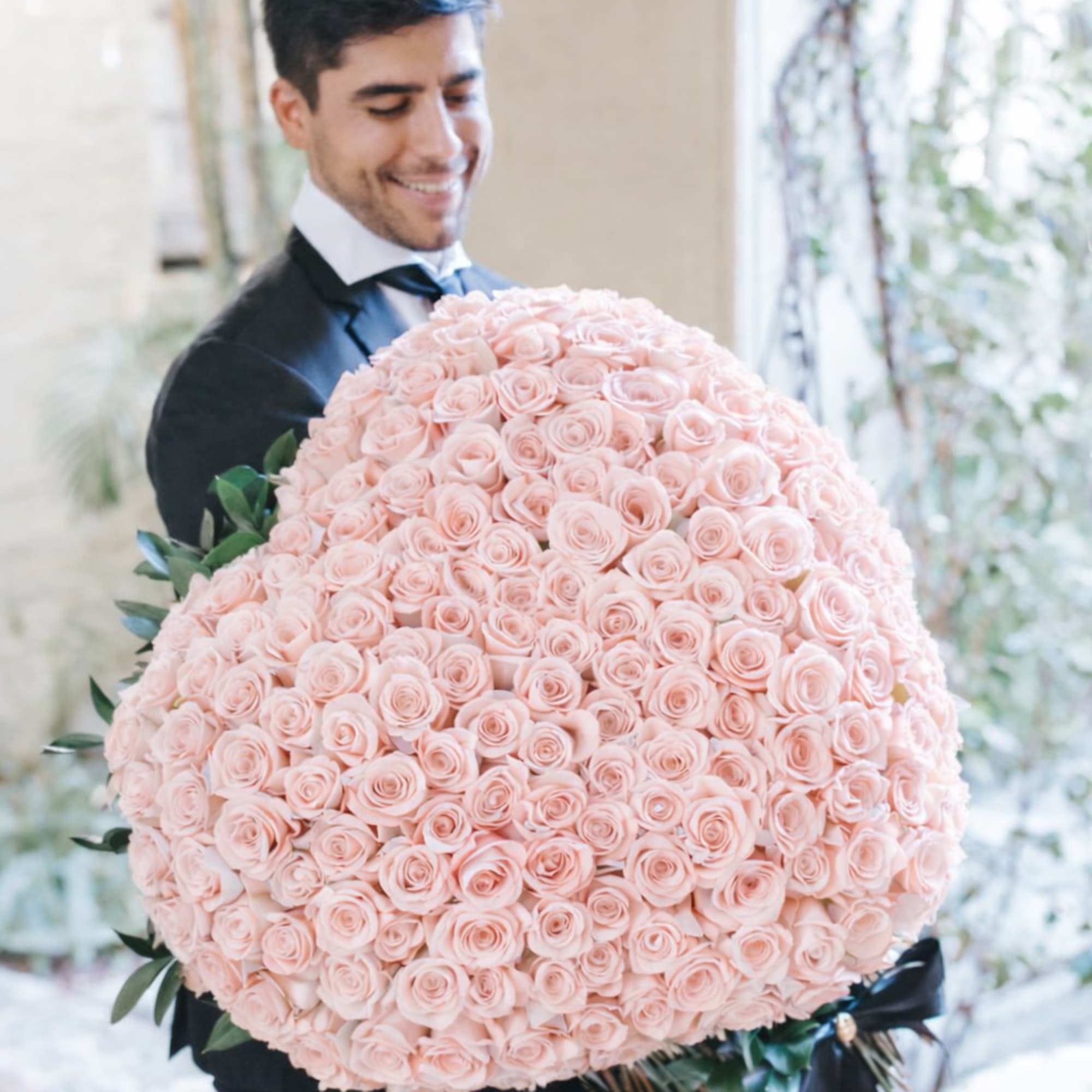 Large pale pink rose bouquet held by a man in formalwear