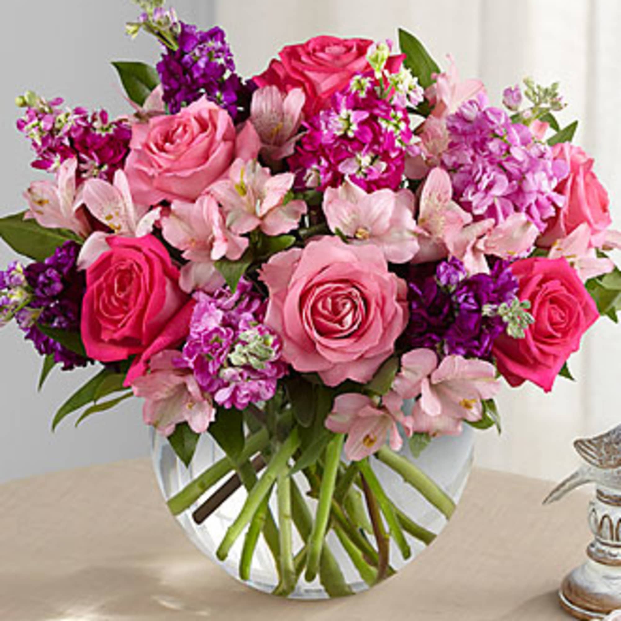 Pink roses and purple flowers in a clear glass vase