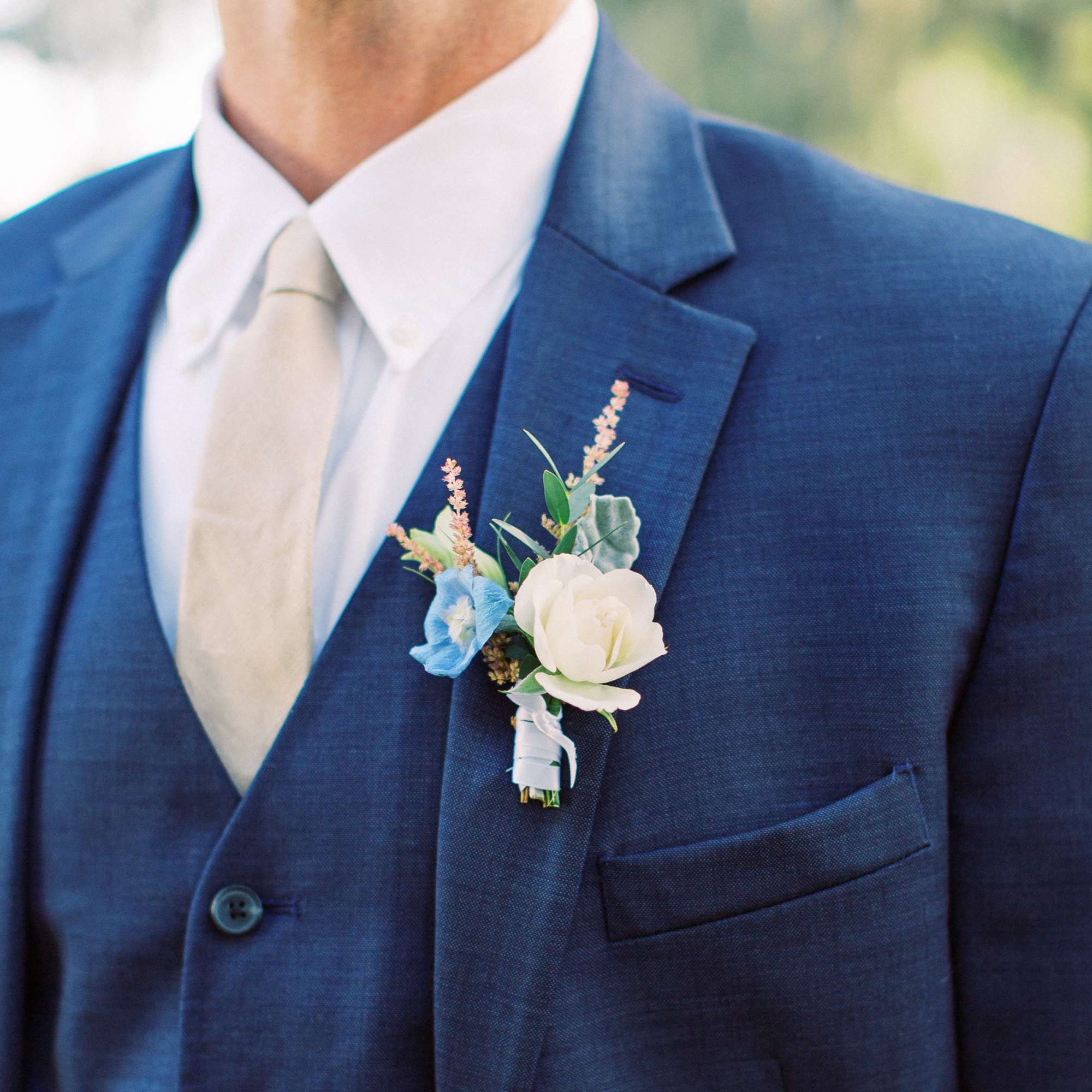 Boutonniere with white and blue flowers on a navy suit lapel