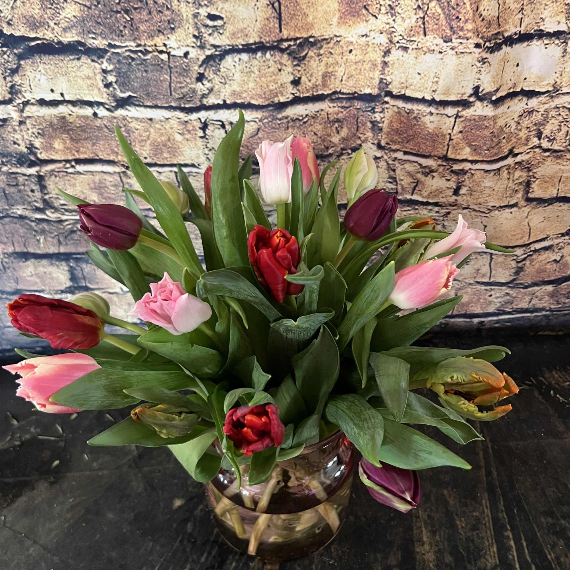 Mixed tulips in pink, red, and purple in a glass vase