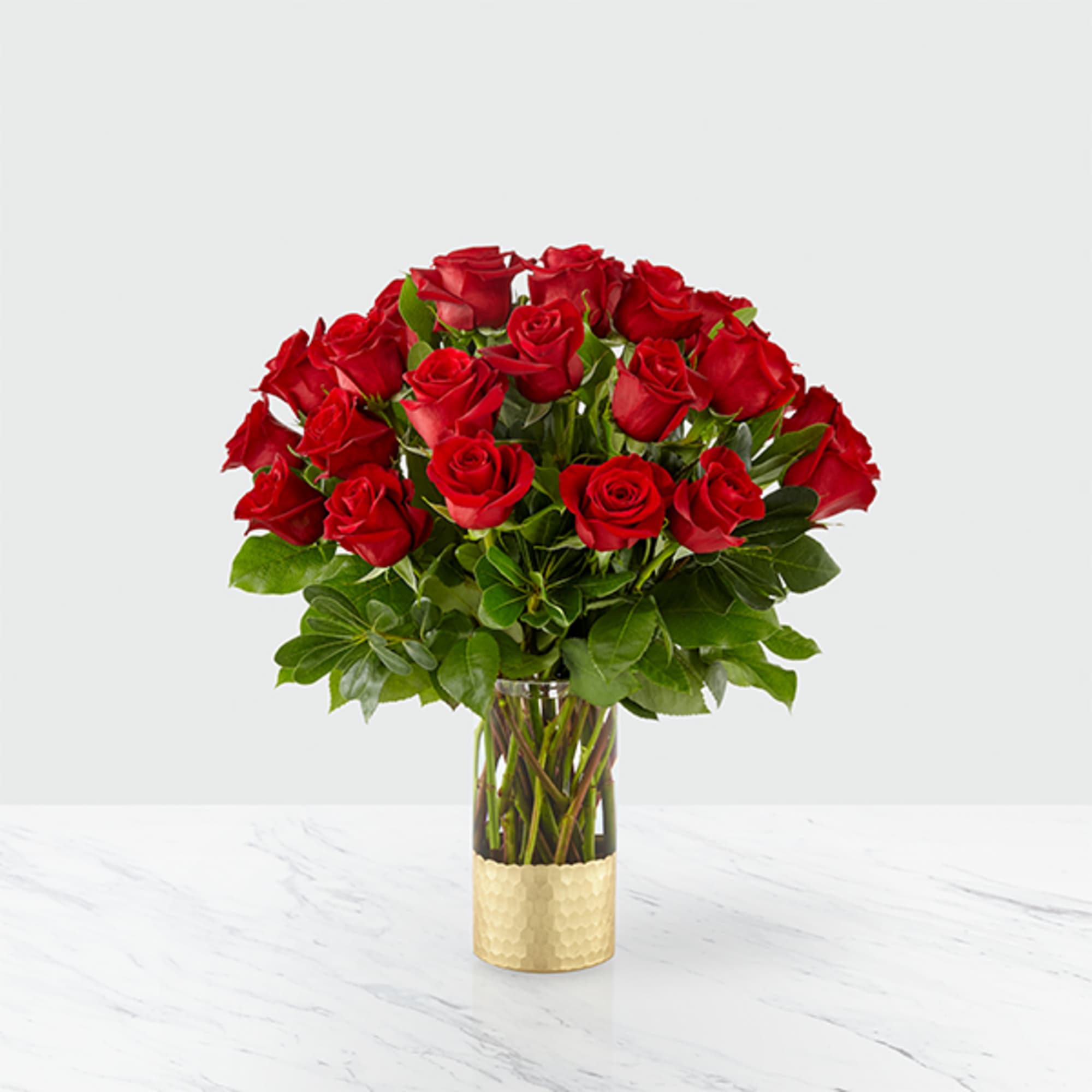 Red roses arranged in a clear glass vase with a gold base