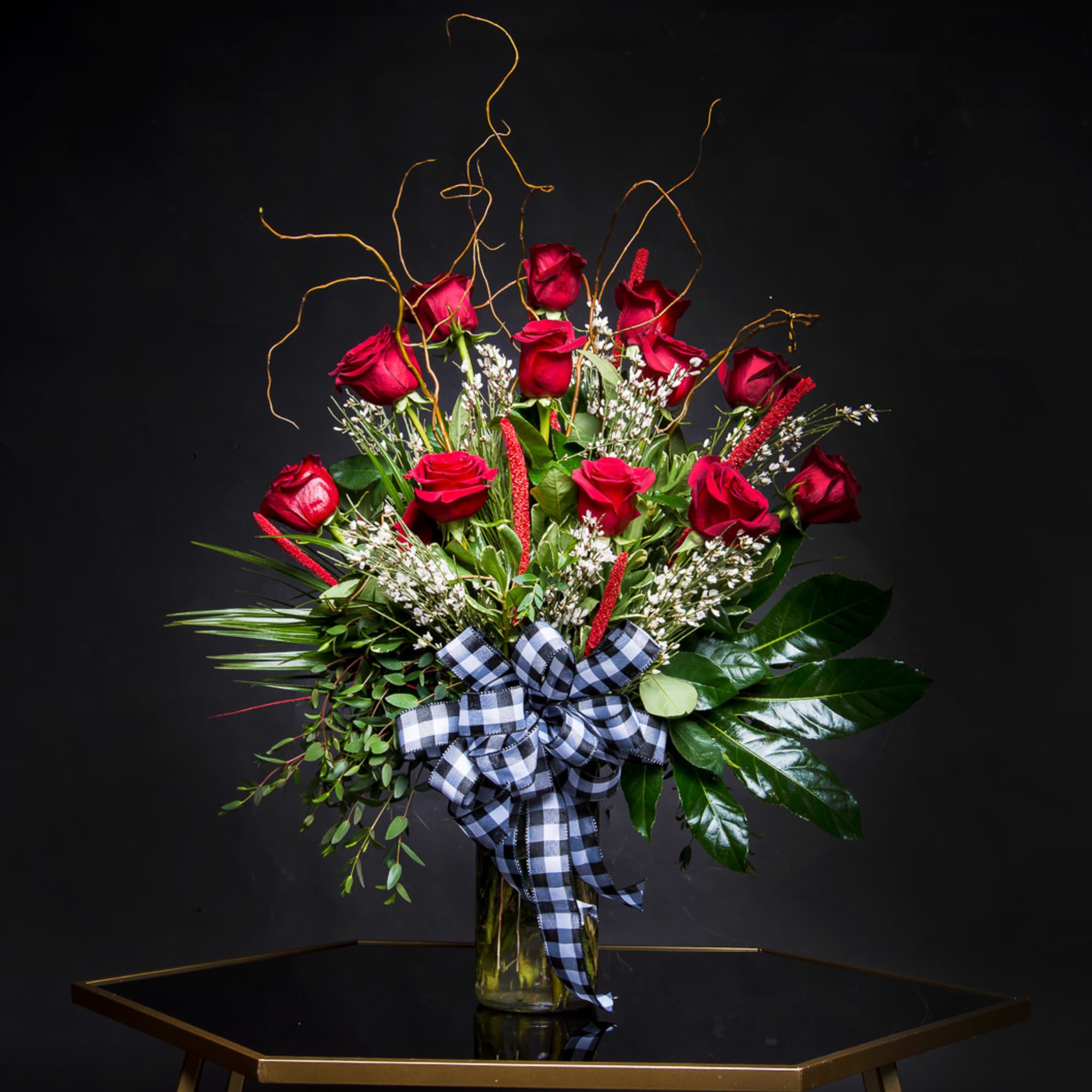 Red roses in a glass vase with a black-and-white ribbon