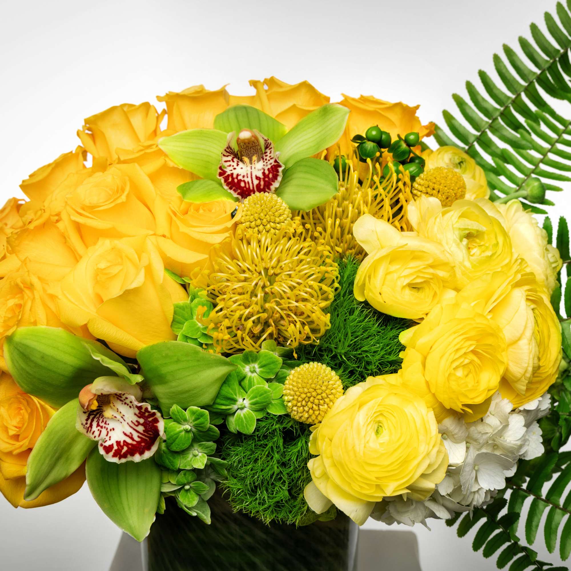 Yellow rose and ranunculus bouquet with green orchids and fern