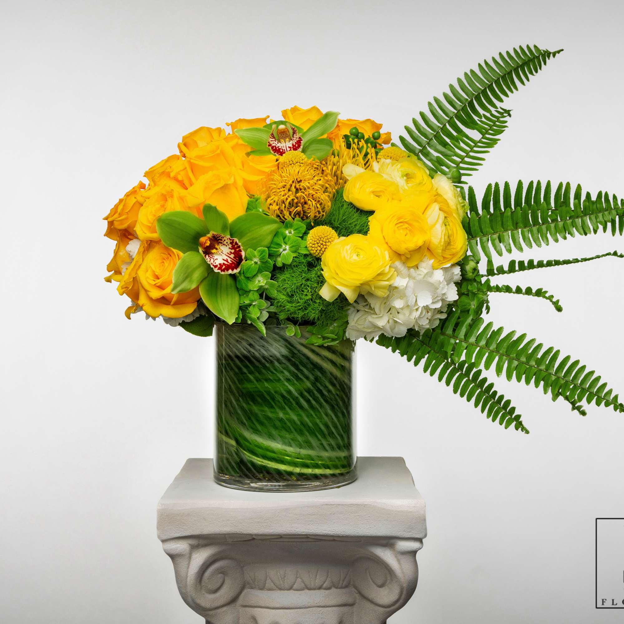 Yellow floral arrangement in a glass vase with fern fronds