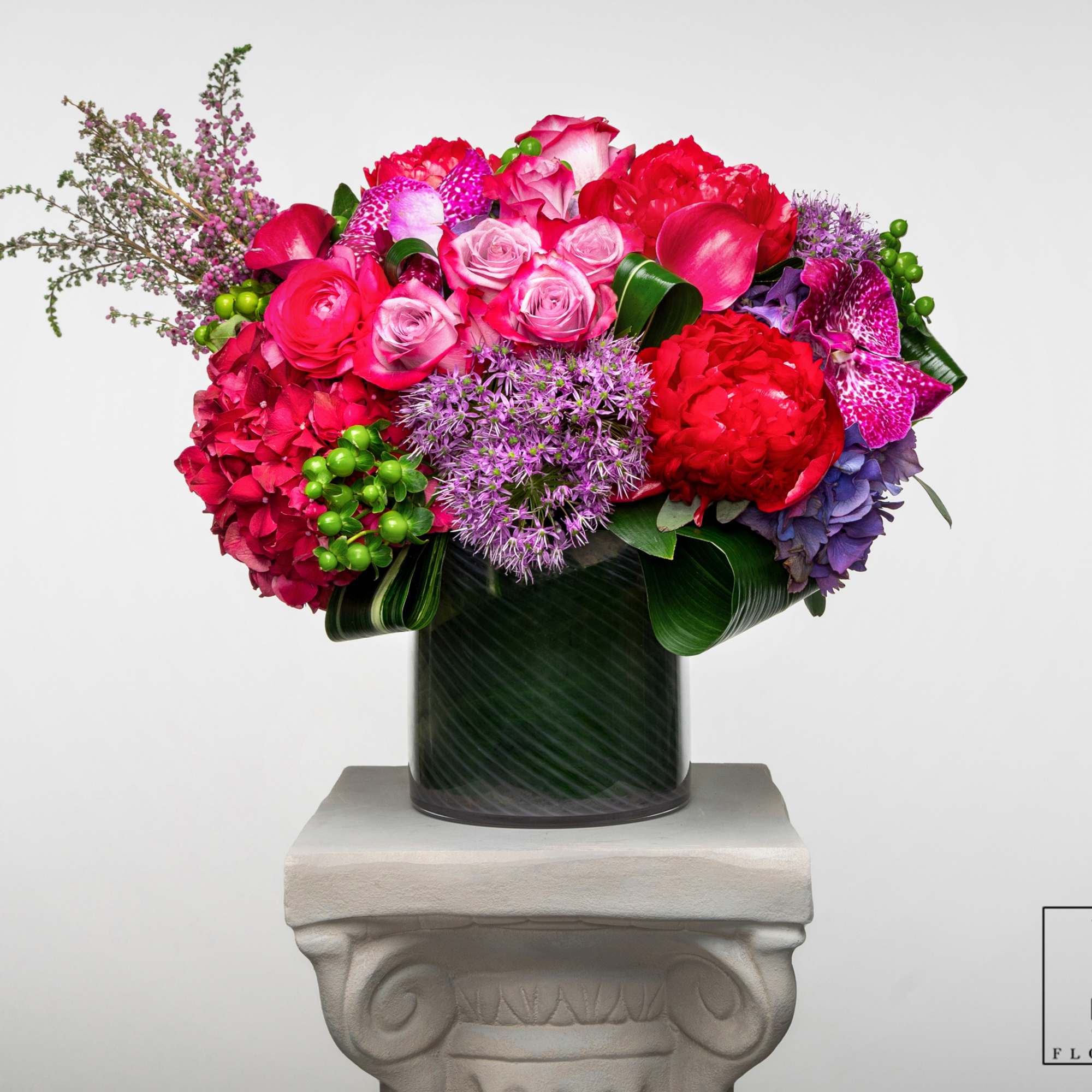Bright mixed bouquet in a dark vase on a pedestal