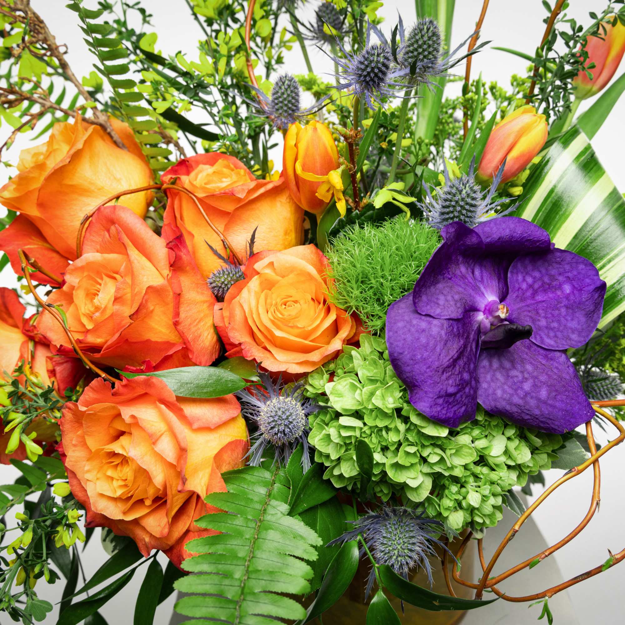 Orange roses and a purple orchid in a mixed bouquet