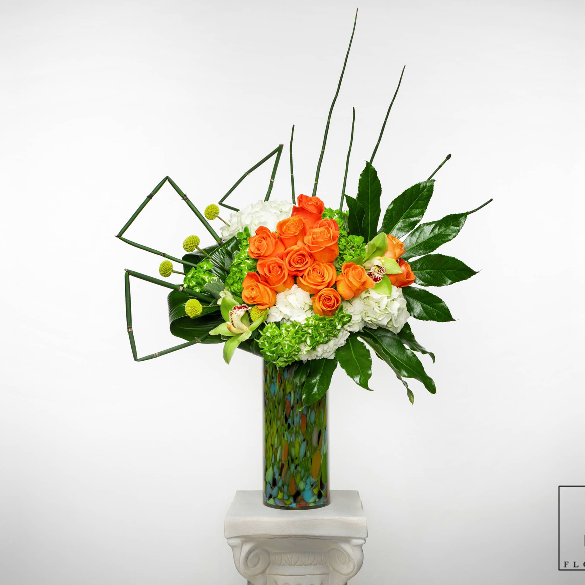 Orange roses and white hydrangeas in a tall patterned vase
