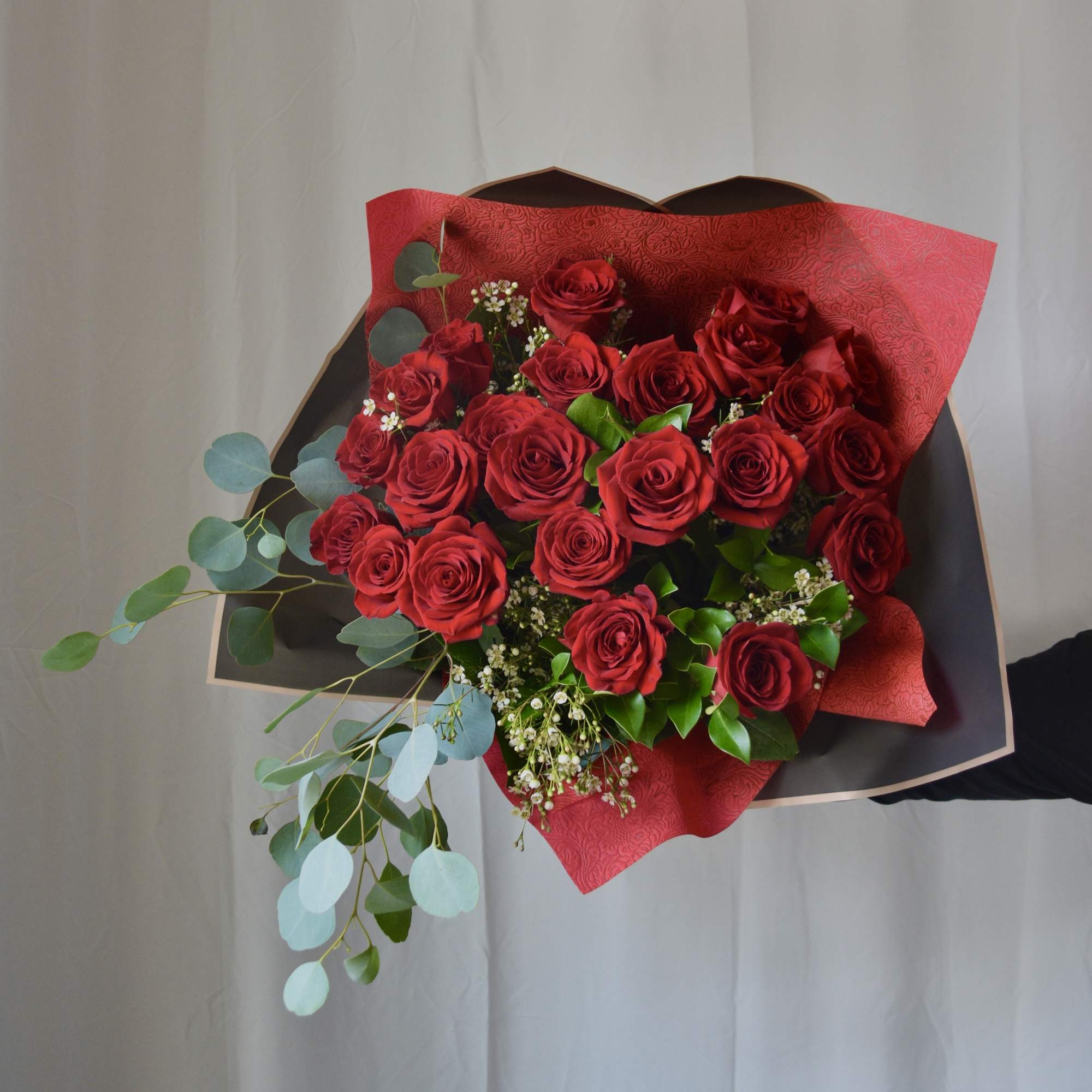 Bouquet of red roses with eucalyptus and red wrapping paper