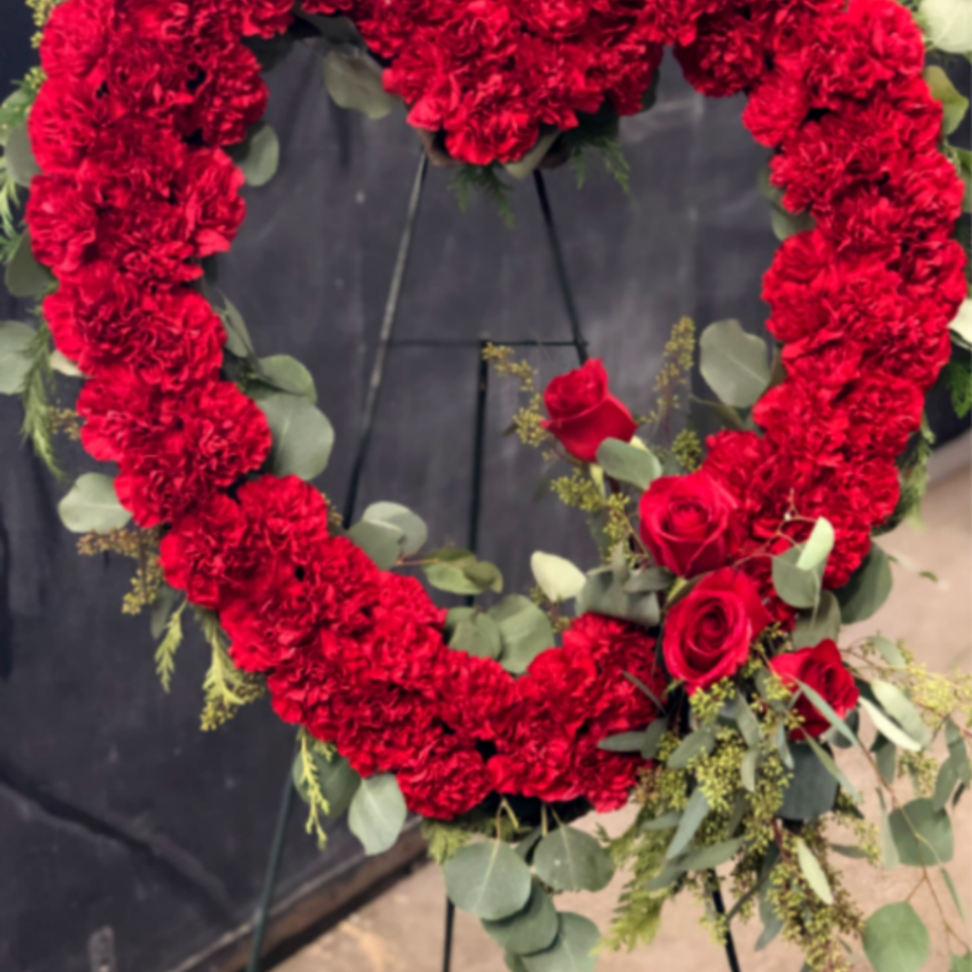 A bold heart of densely packed red carnations-accented with a cluster of