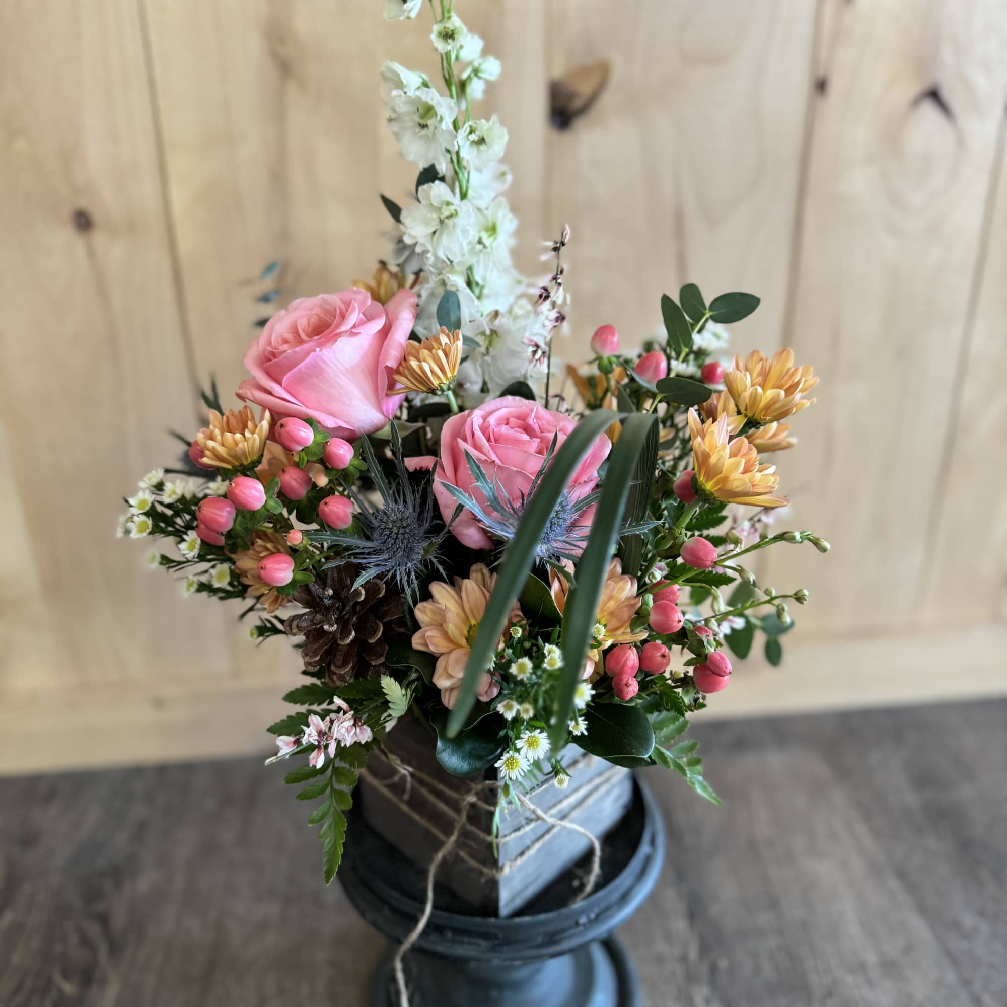 Pink roses and mixed flowers arranged in a dark vase