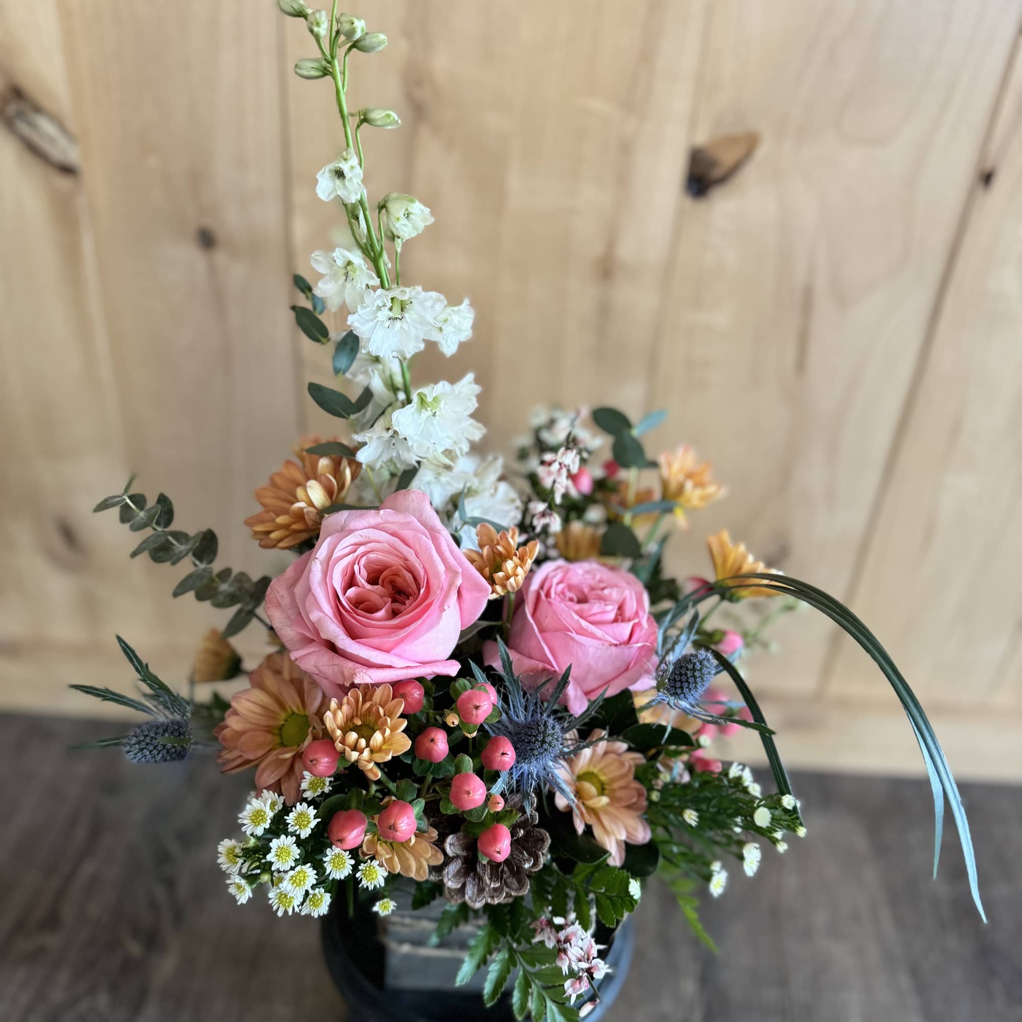 Pink roses in a mixed floral arrangement with white blooms in a black container