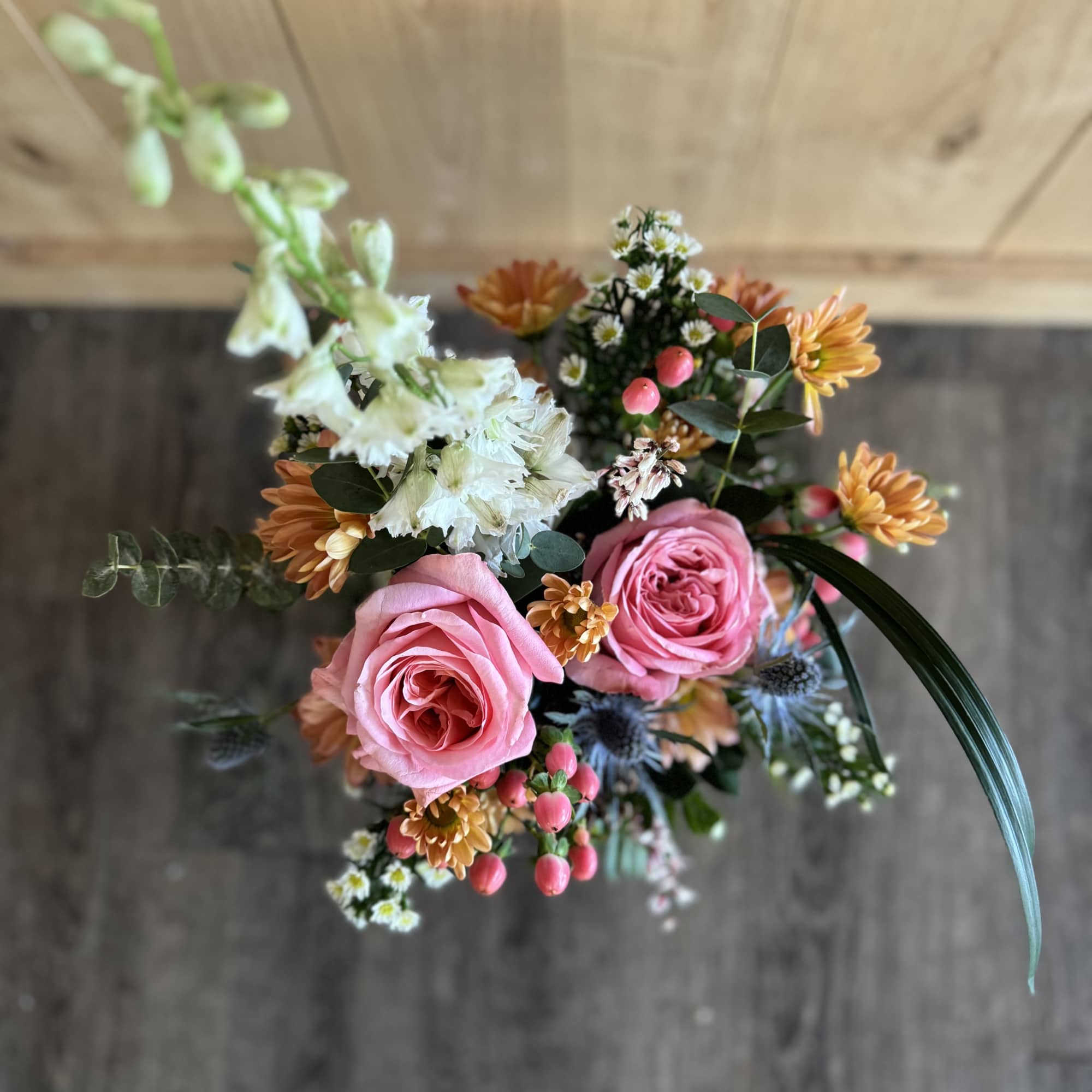 Pink roses with orange daisies and white flowers in a hand-tied bouquet
