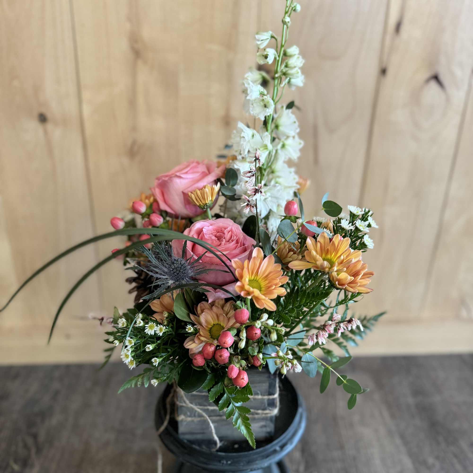 Mixed bouquet with pink roses, peach daisies, and white spikes in a black vase