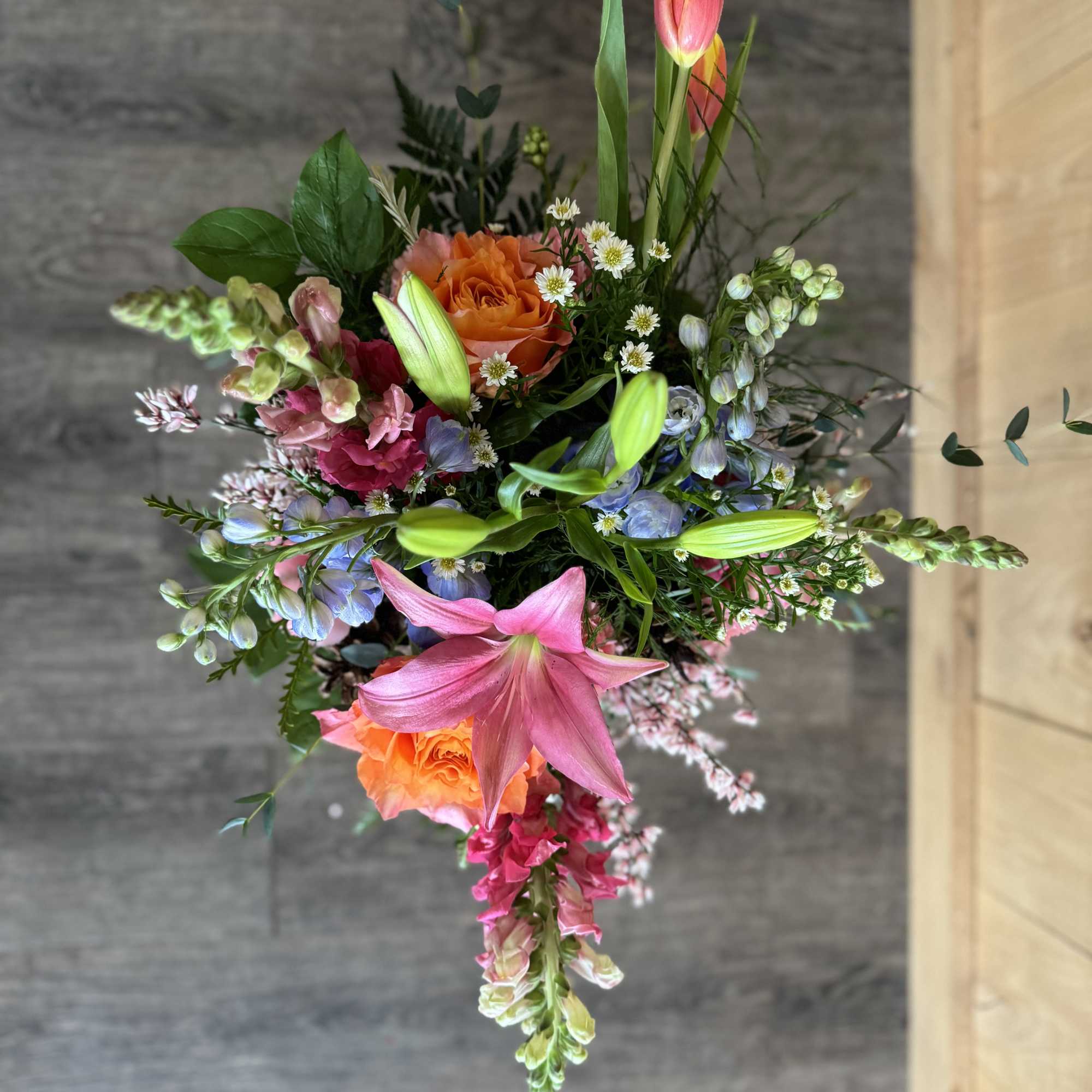 Mixed bouquet with pink lilies, orange roses, and small white daisies