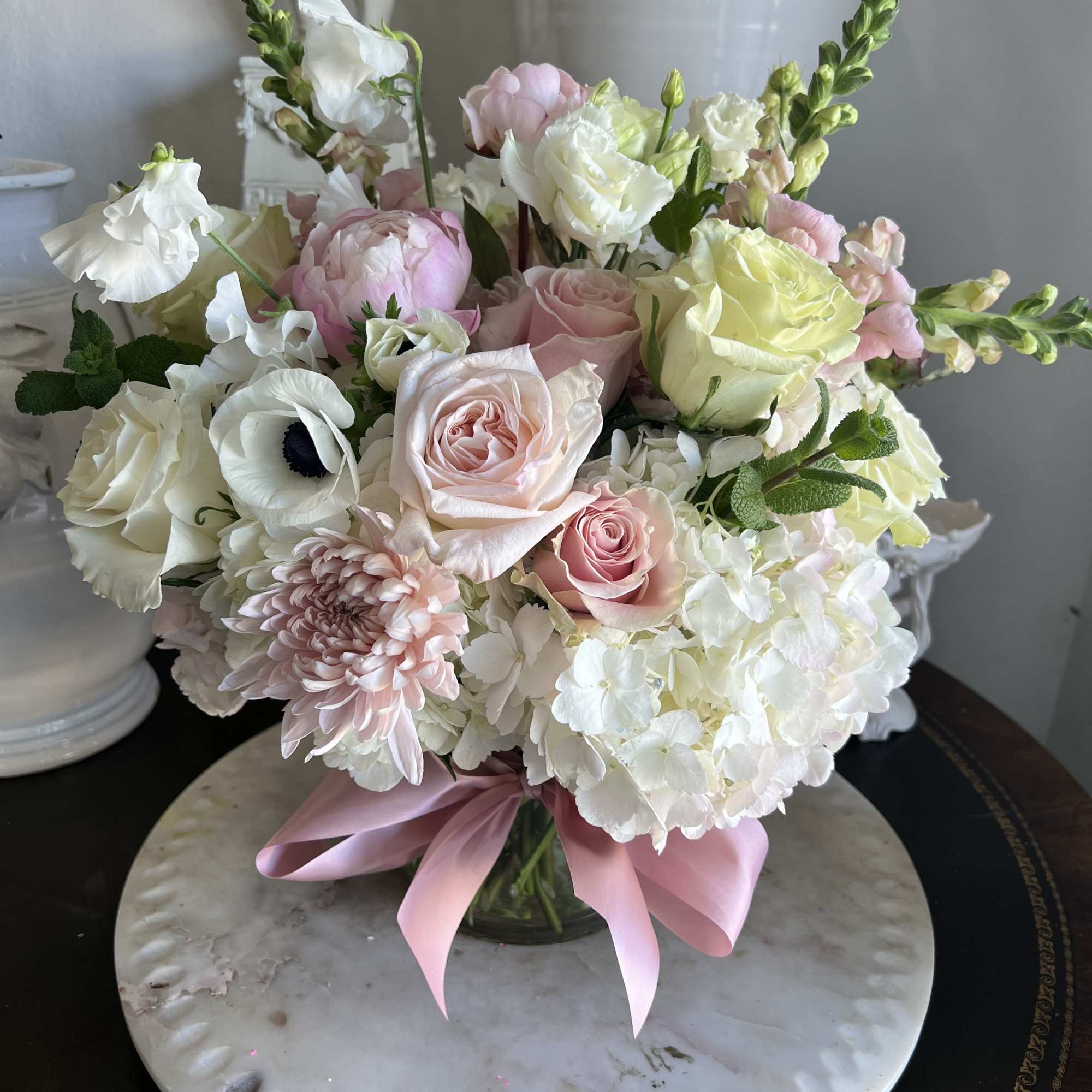 Pink and white mixed bouquet in a glass vase with a pink ribbon