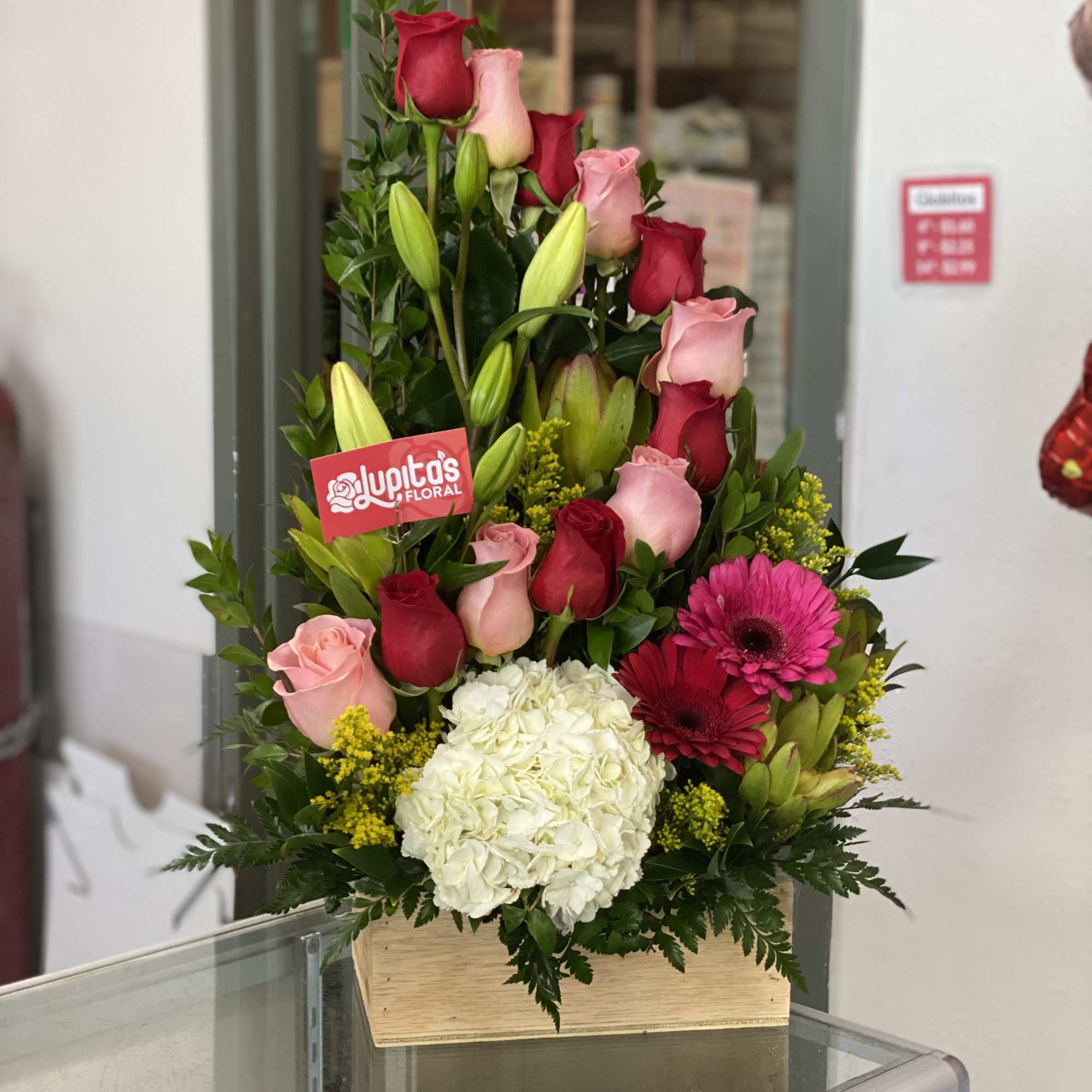 Tall bouquet of pink and red roses with white hydrangea in a wooden box
