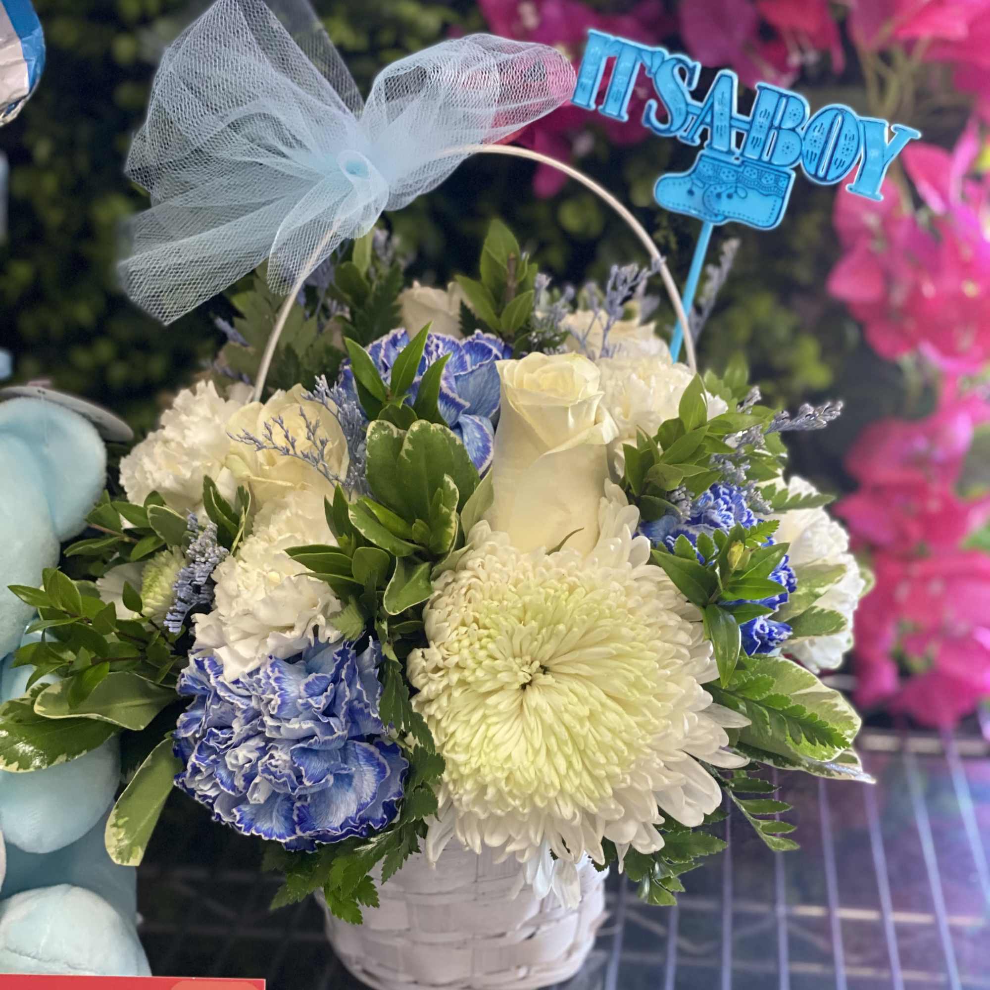 Basket arrangement of white, blue, and cream flowers with a "It's a Boy" topper