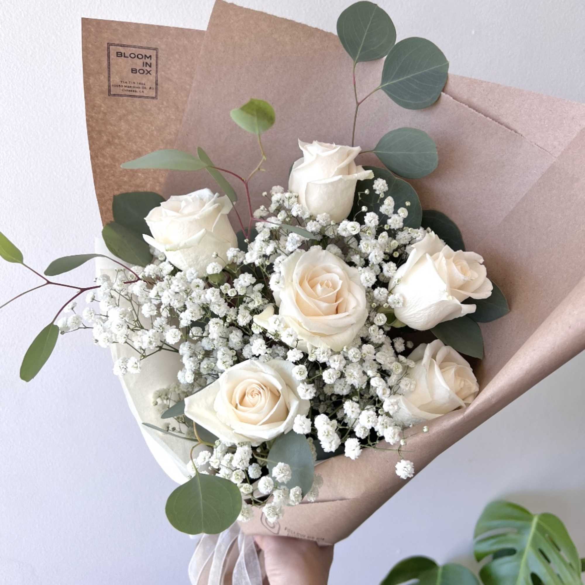 Bouquet of white roses with baby's breath and eucalyptus in brown paper