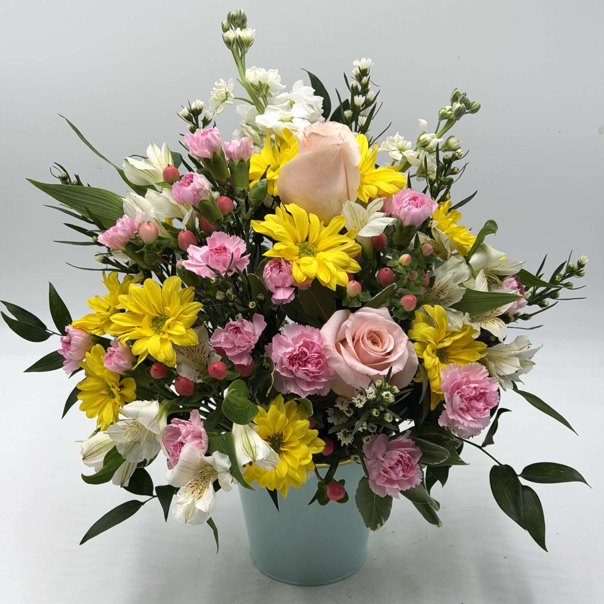 A cheerful blend of yellow daisies, soft peach roses, light pink mini