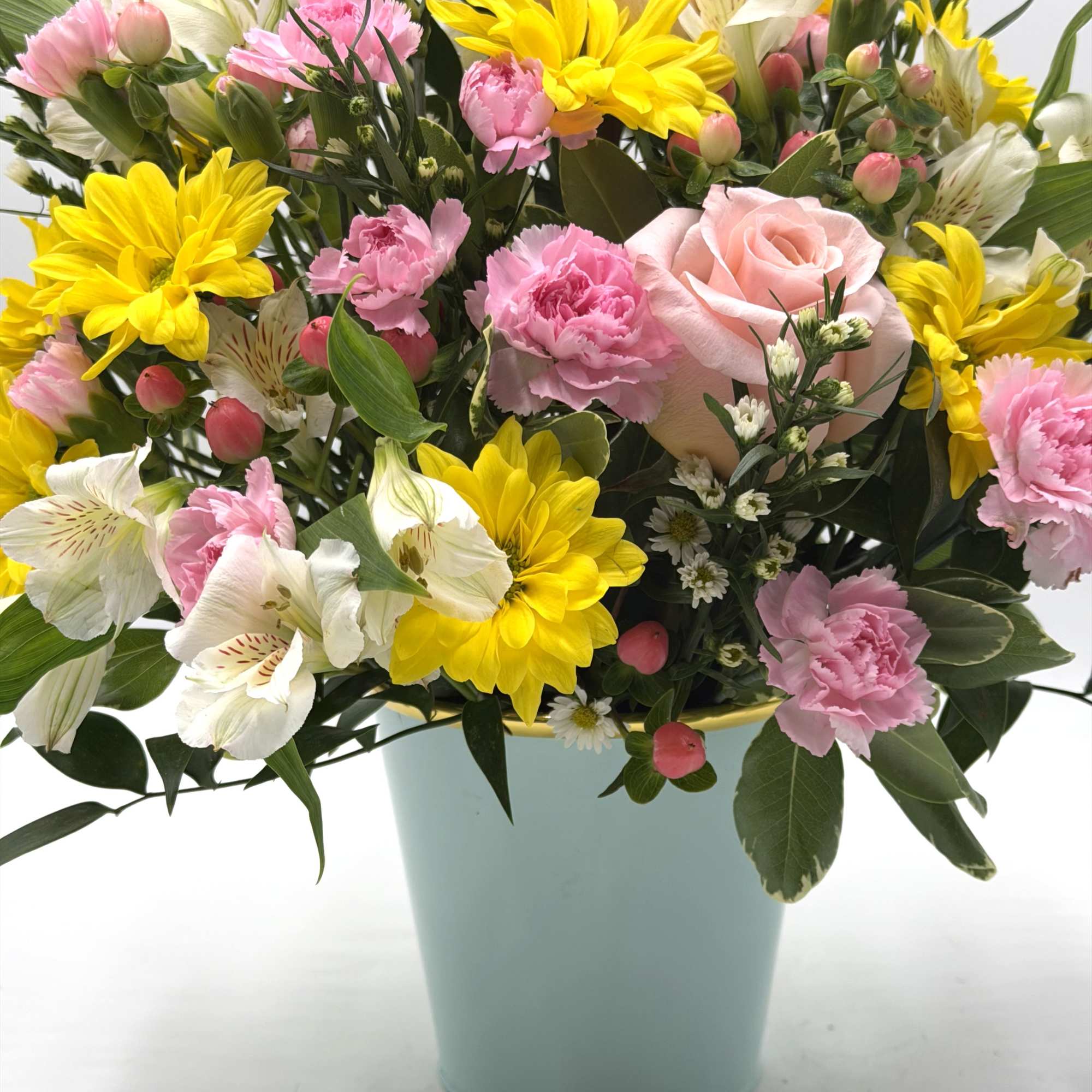 A cheerful blend of yellow daisies, soft peach roses, light pink mini