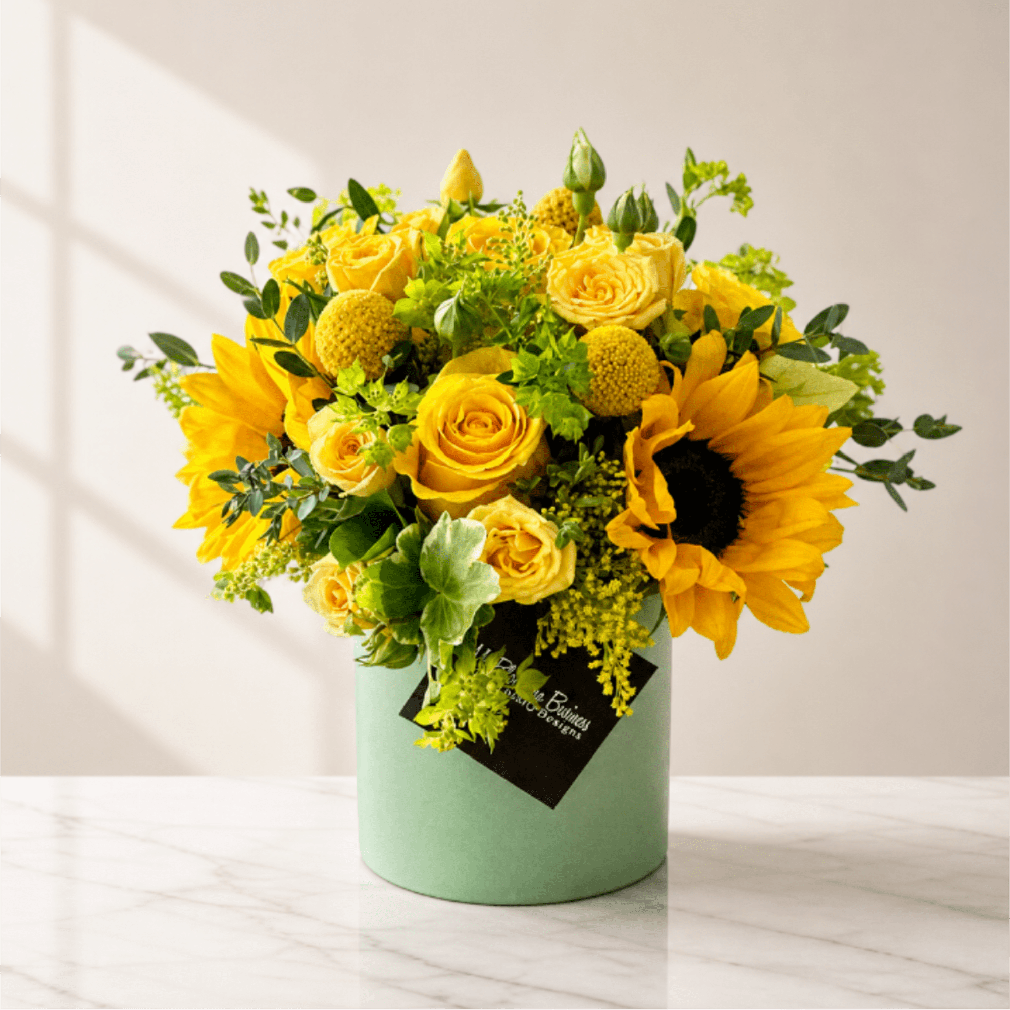 Yellow roses and sunflowers arranged in a mint green box