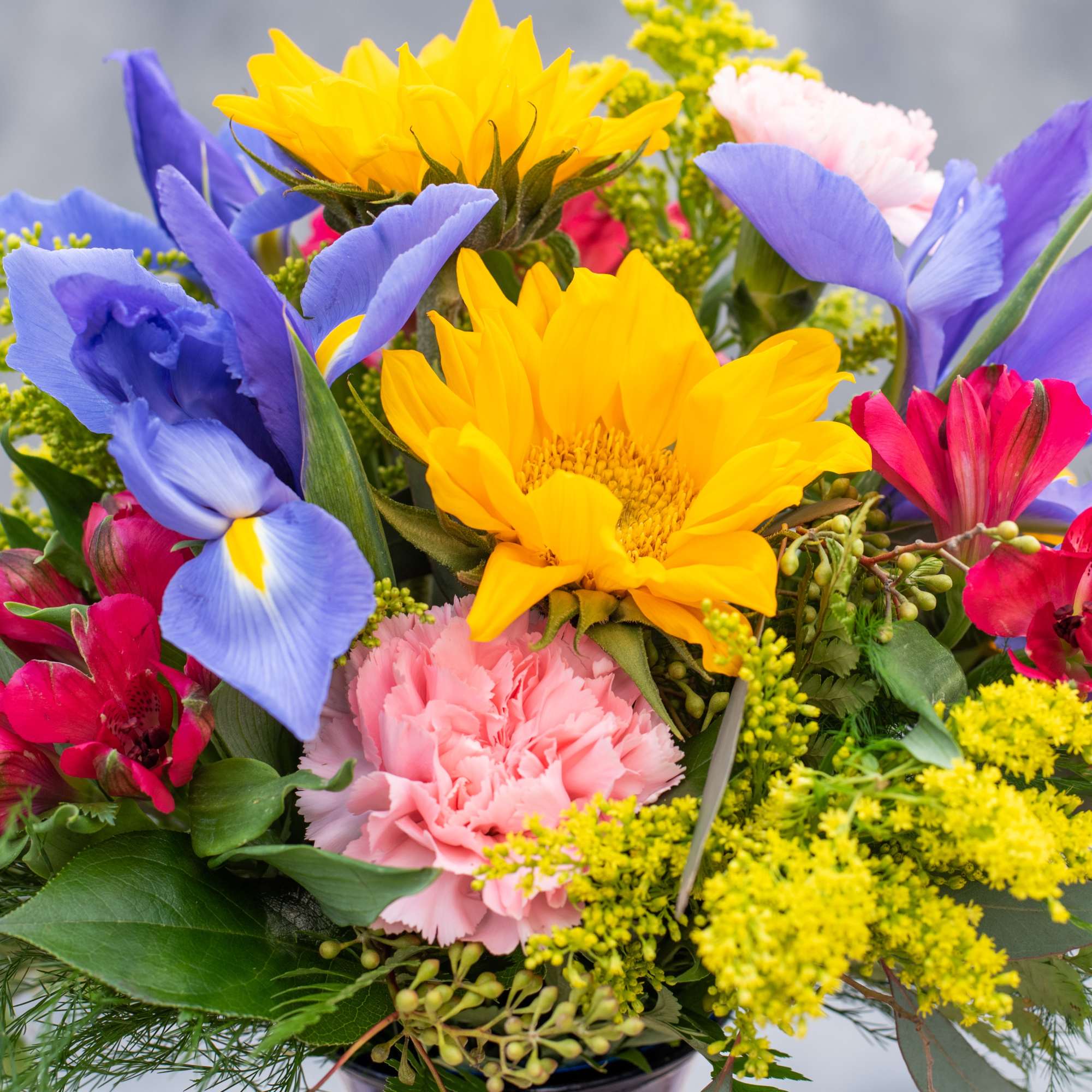 Bright mixed bouquet with sunflowers, blue irises, and pink carnations