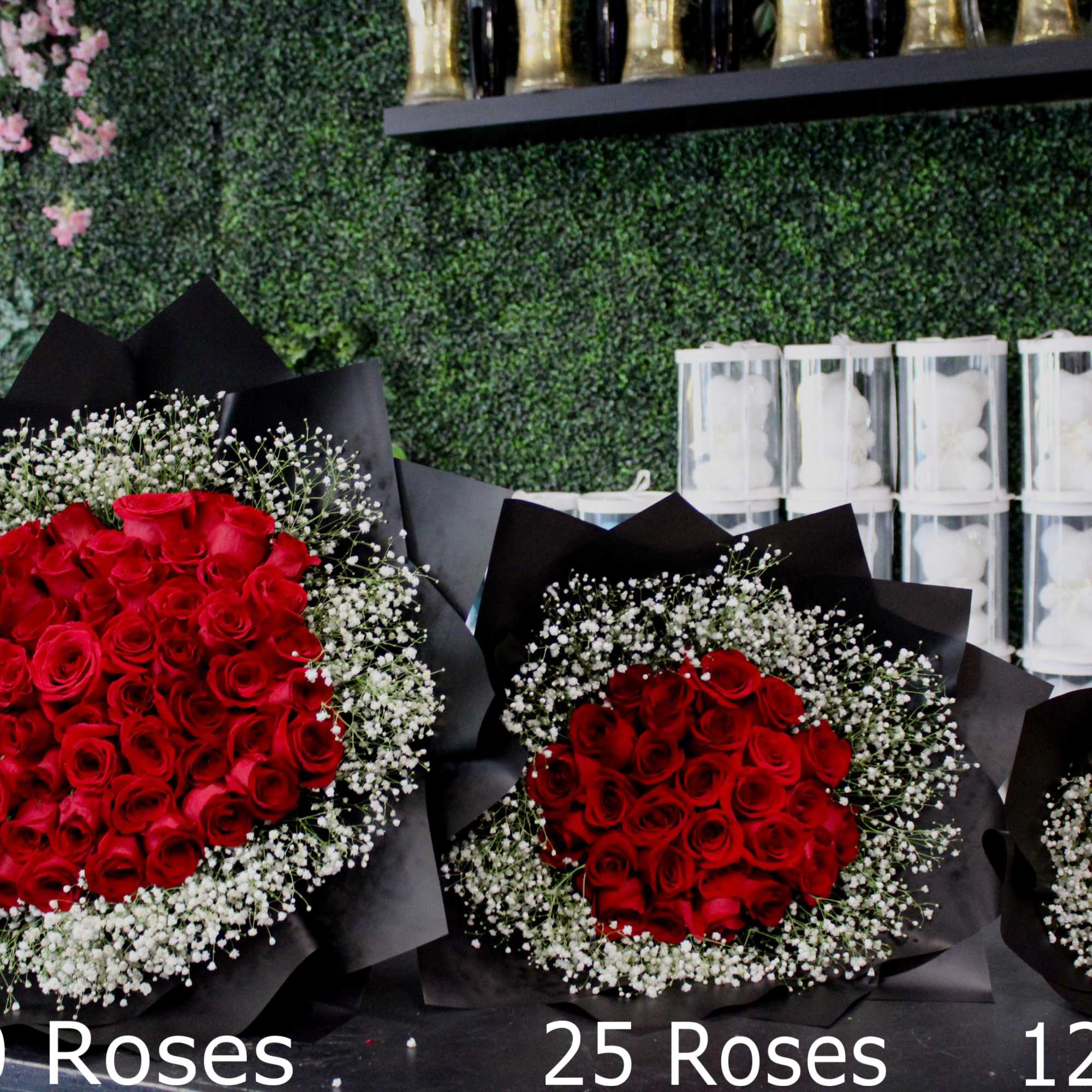 Three bouquets of red roses with baby's breath in black wrap