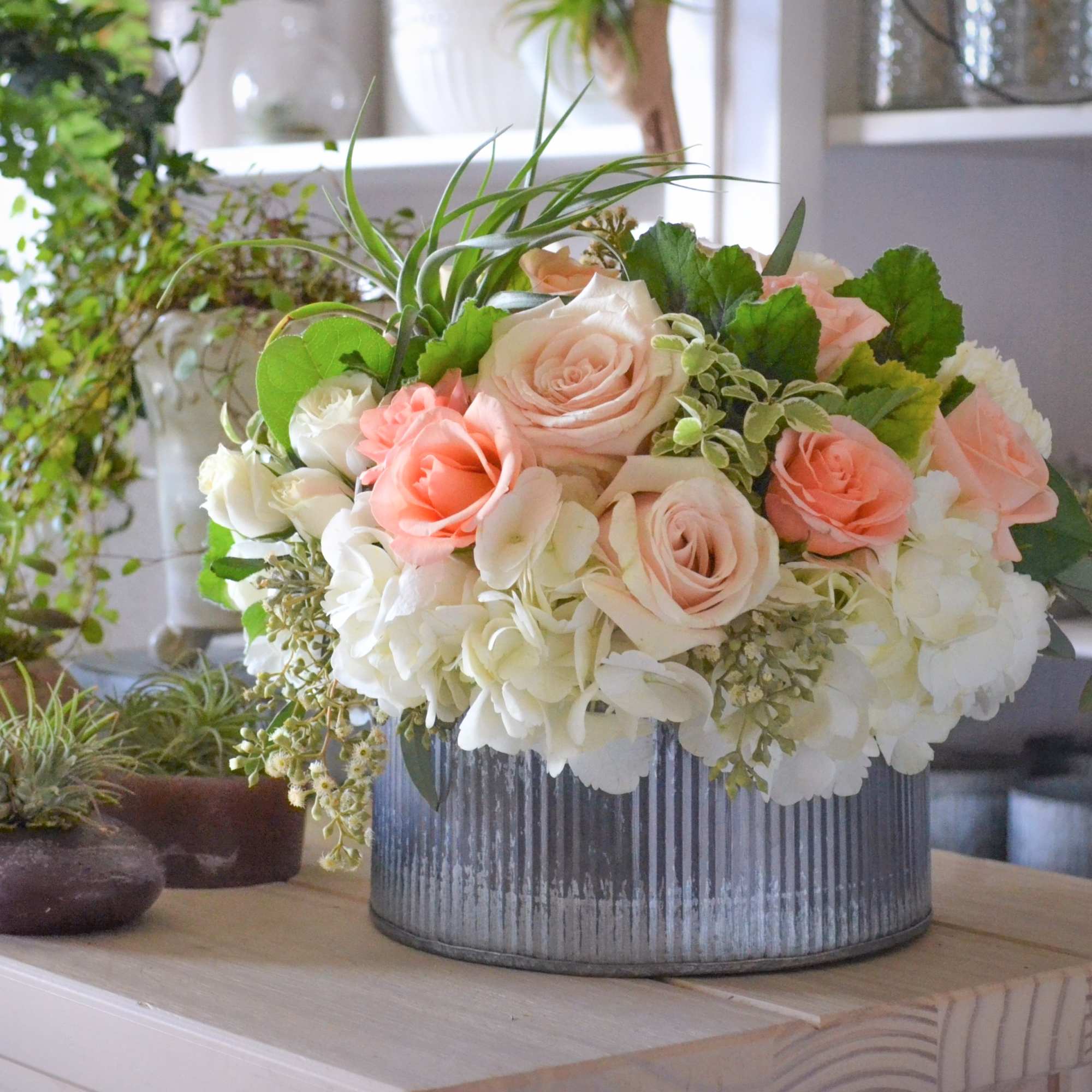 Peach and white rose arrangement in a ribbed metal container