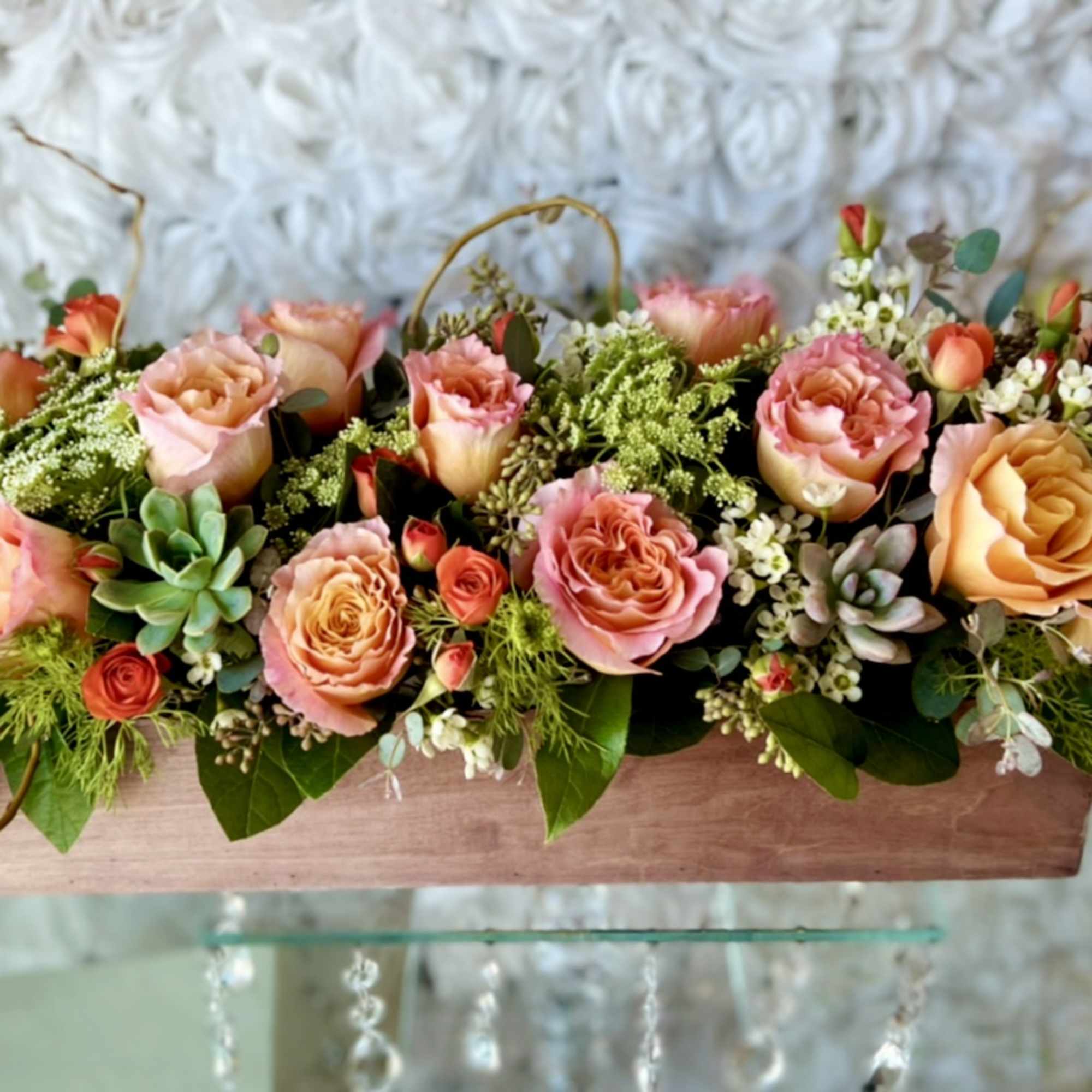 Low floral centerpiece with pink and peach roses in a wooden box