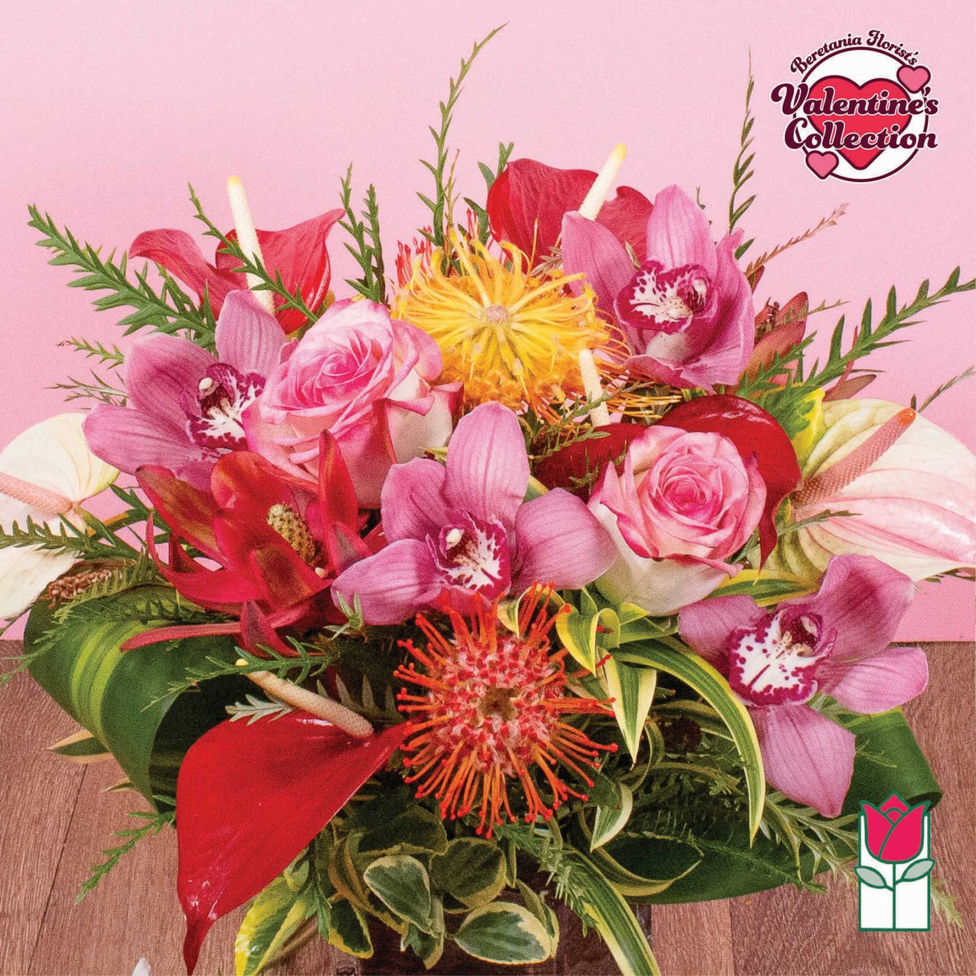 Low arrangement of pink roses, orchids, red anthuriums and orange pincushion blooms in a compact vase
