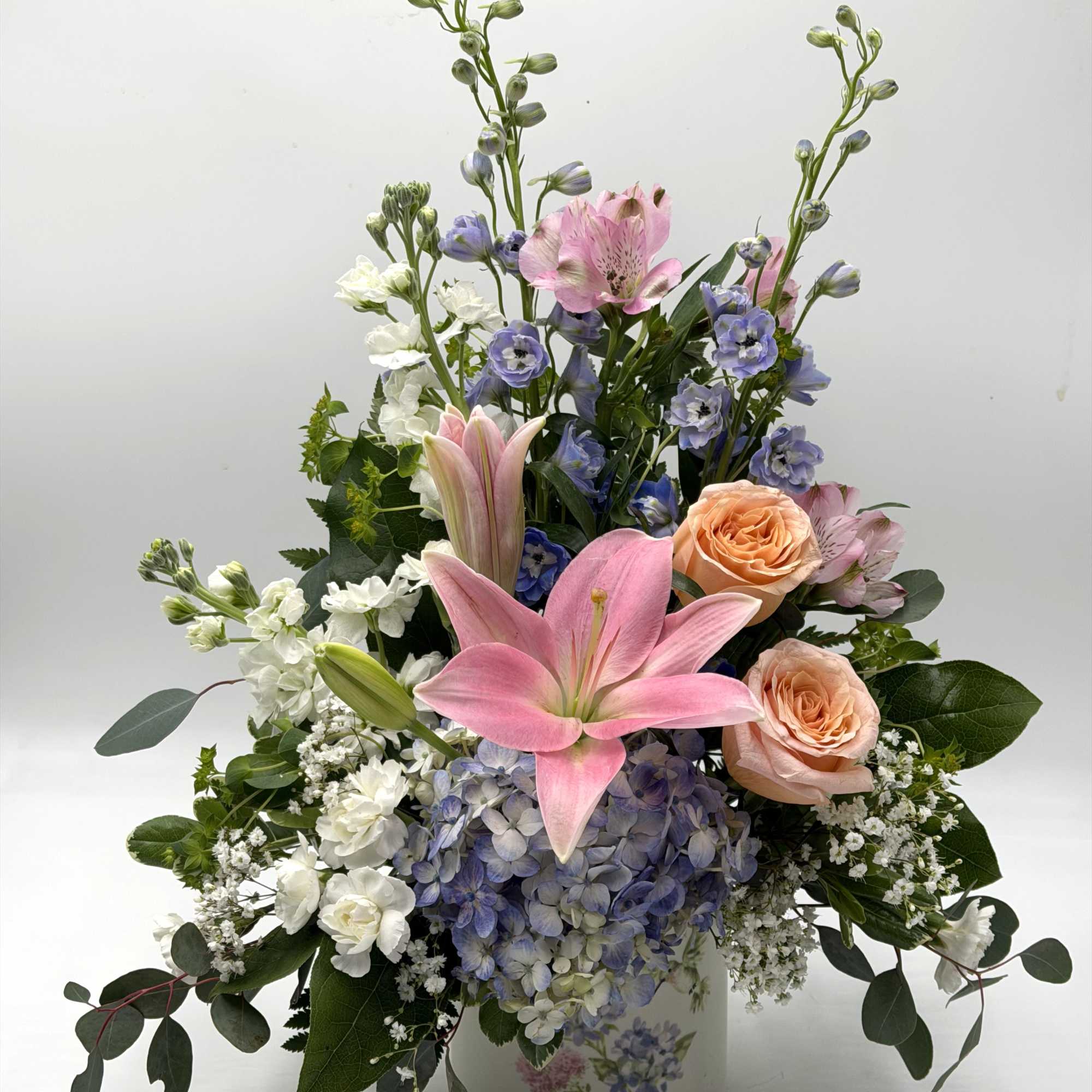 A soft &amp; elegant garden-style arrangement featuring pink lilies, blush peach roses
