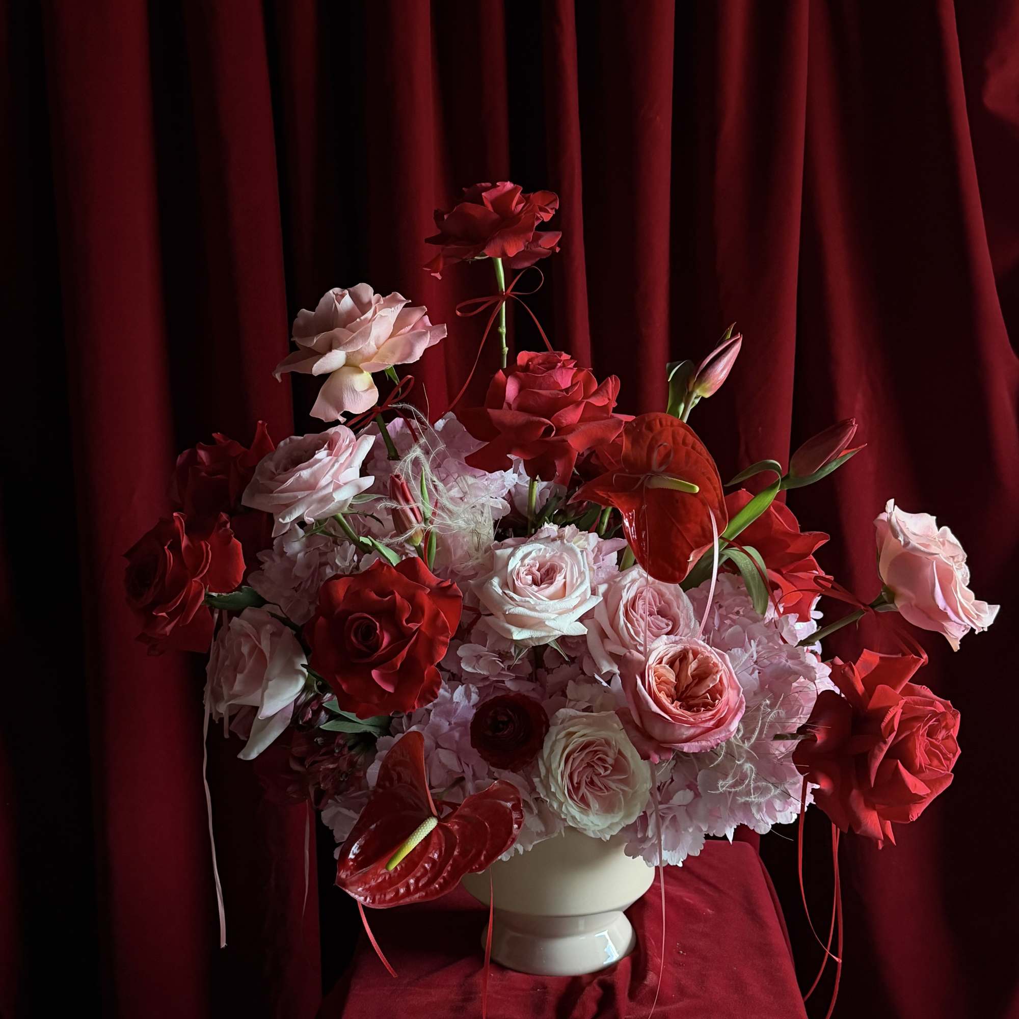 Red and pink rose arrangement in a white vase
