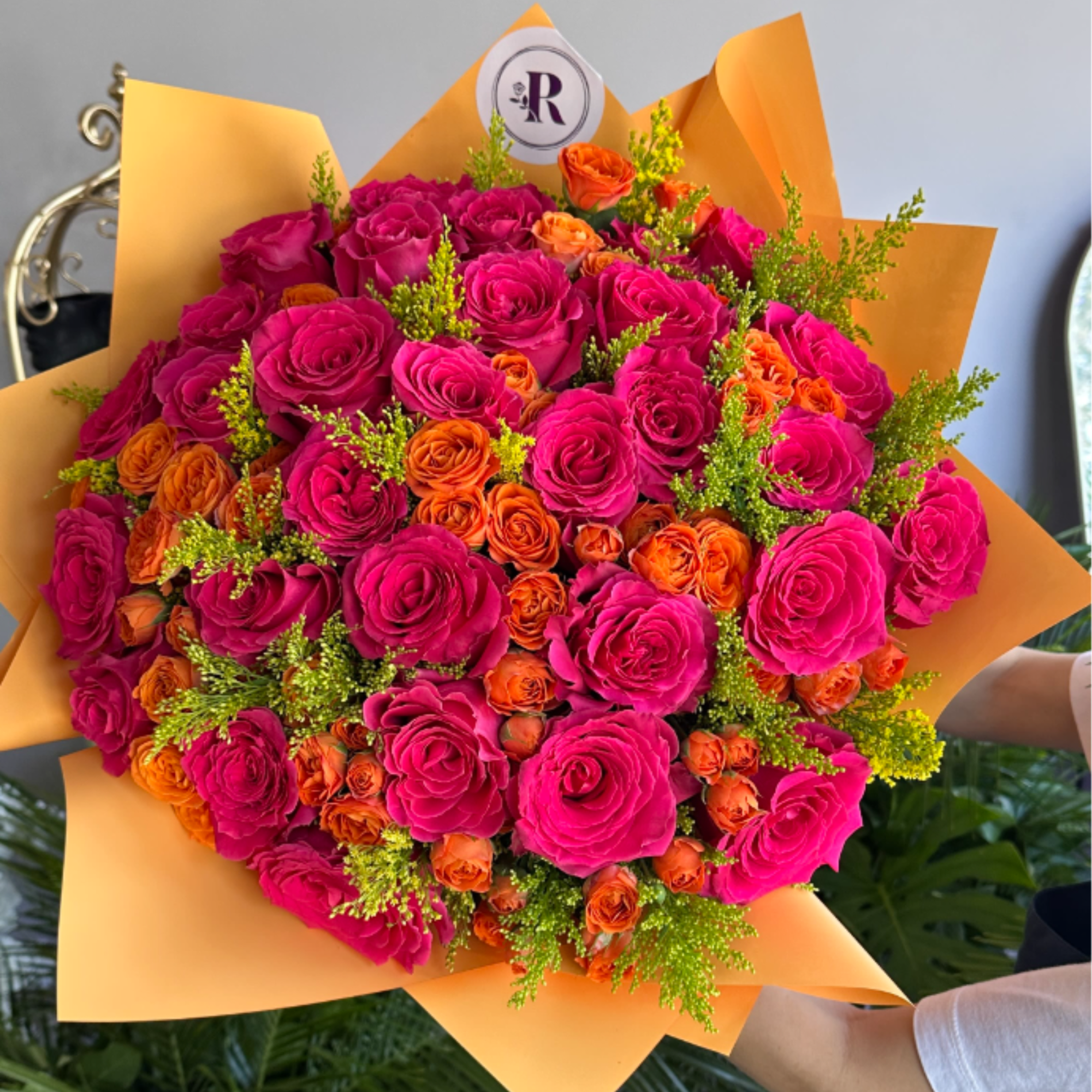 A radiant fall bouquet featuring fuchsia colored and orange roses, golden solidago