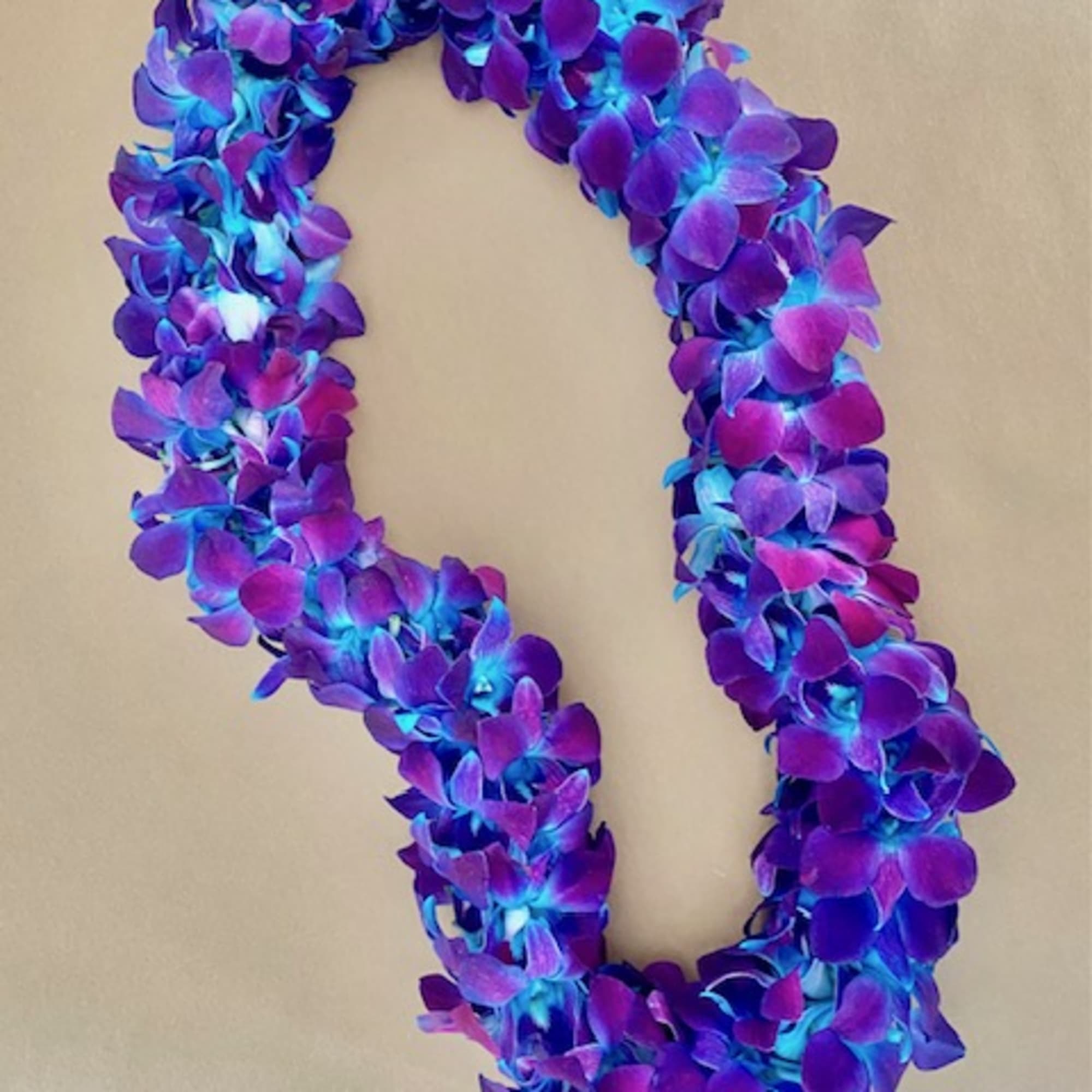 Purple and blue floral lei on a neutral background