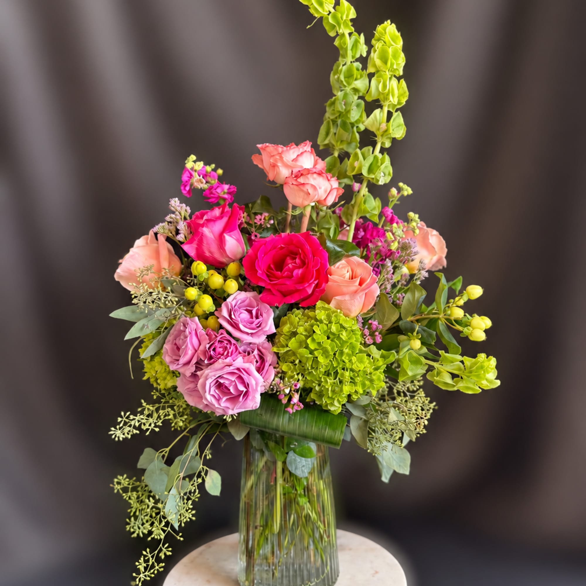 Bright pink and blush roses pair with a vivid green hydrangea cluster