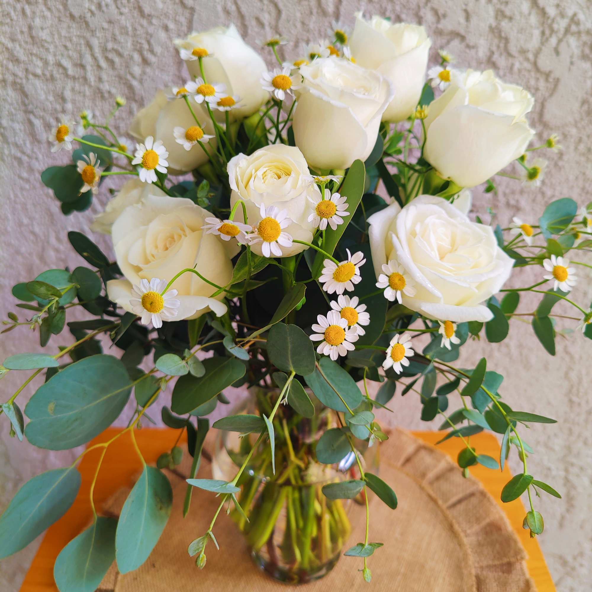 White roses and small daisy flowers in a glass vase