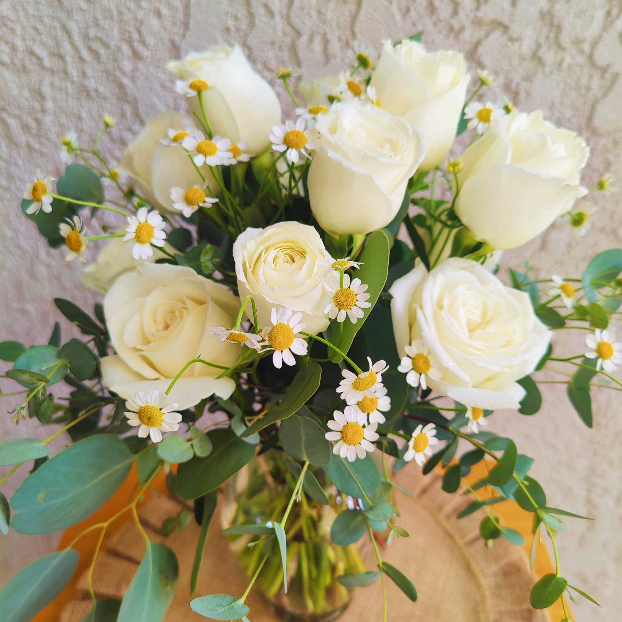 White roses and small daisies in a glass vase